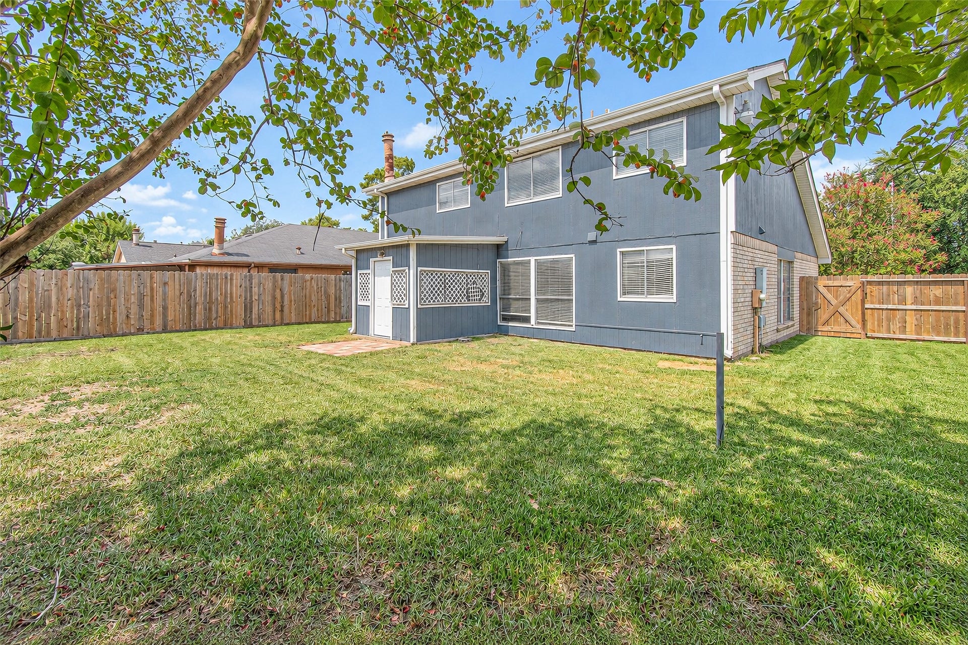 12027 Huntington Park Drive, Houston, TX 77099 Spacious backyard with lush green lawn and a charming two-story home, perfect for outdoor activities and relaxation.
