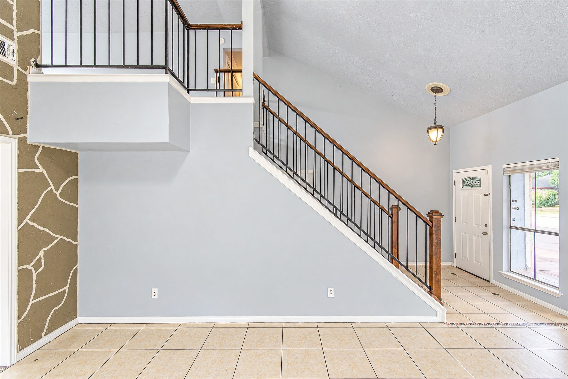 12027 Huntington Park Drive, Houston, TX 77099 Spacious entryway features a striking staircase with elegant railing, complemented by tiled floors and abundant natural light from large windows.