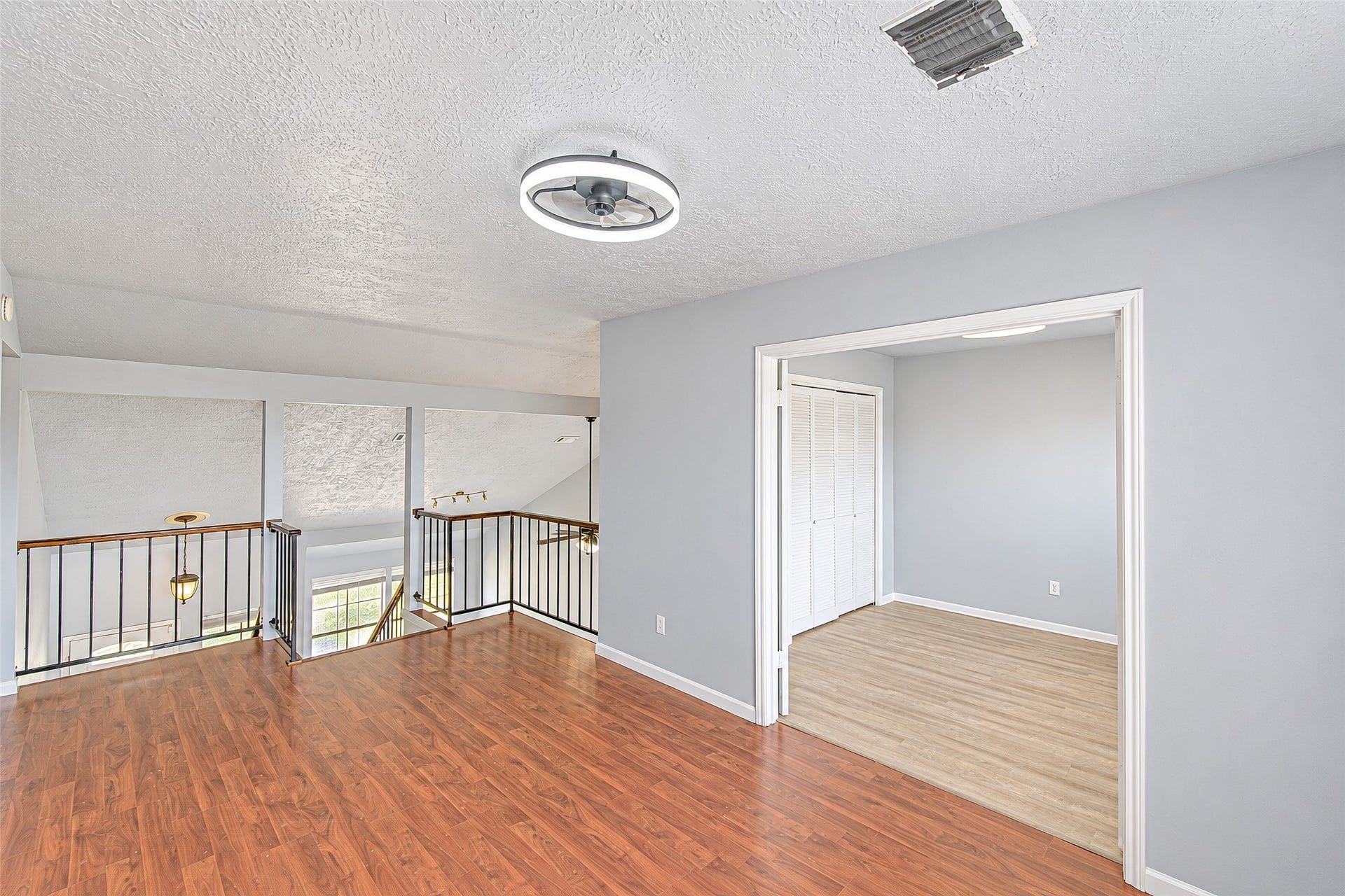 12027 Huntington Park Drive, Houston, TX 77099 Bright and airy loft space with beautiful wood flooring, modern light fixture, and ample natural light from large windows, perfect for a cozy retreat or home office.