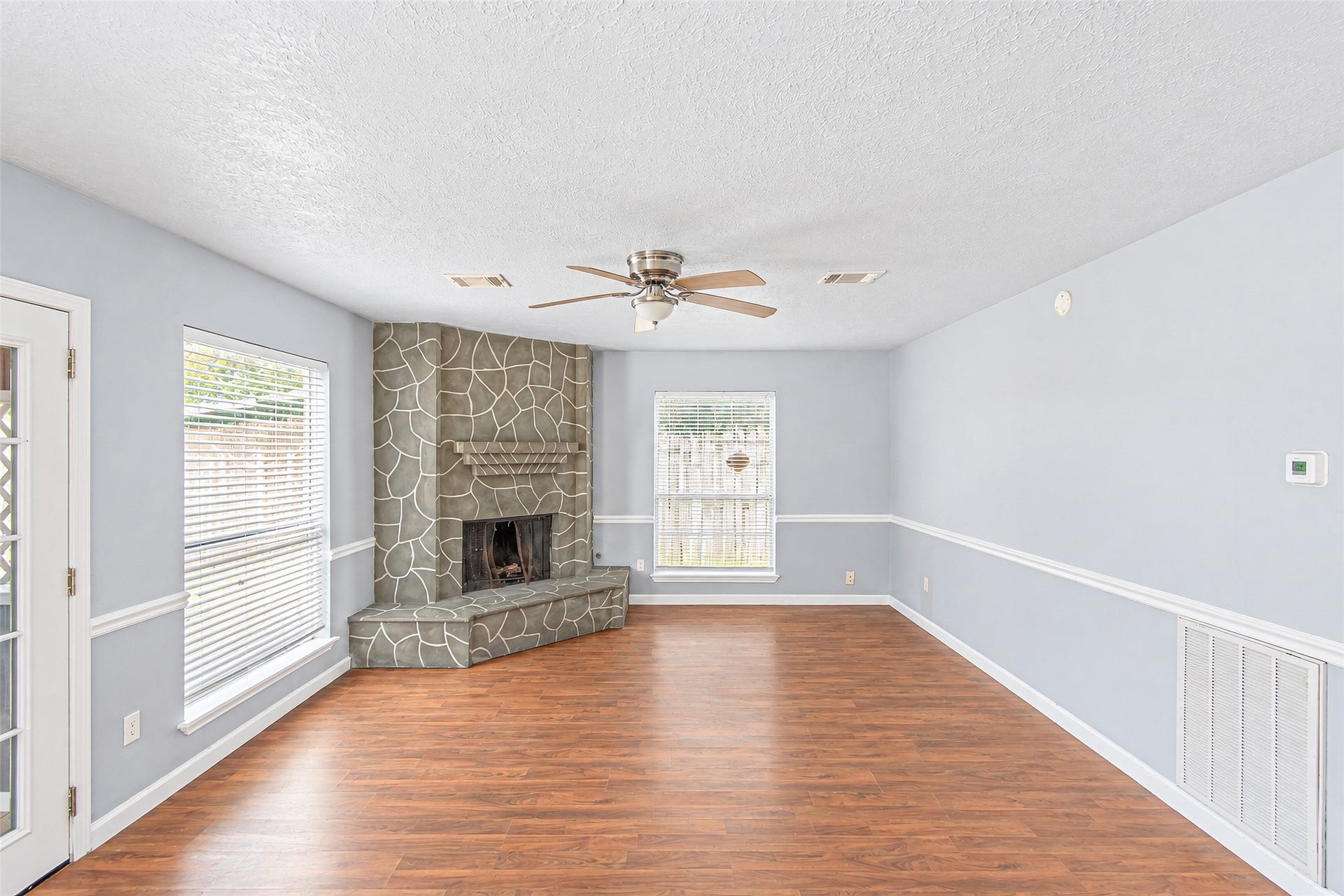 12027 Huntington Park Drive, Houston, TX 77099 Bright and inviting living room featuring a unique stone fireplace, hardwood floors, and ample natural light from large windows.