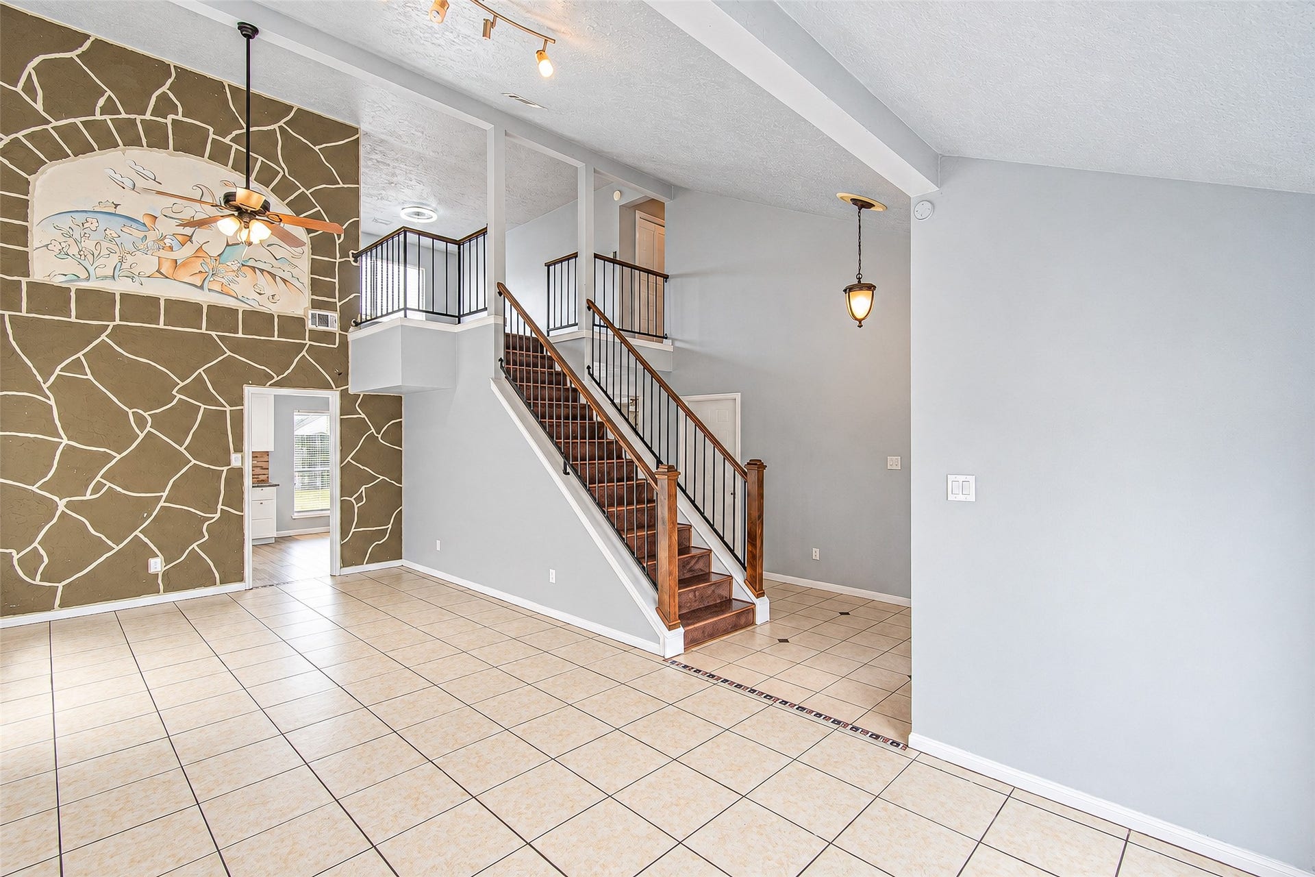 12027 Huntington Park Drive, Houston, TX 77099 Spacious living area with high ceilings and a decorative accent wall, featuring a striking staircase with wooden steps and elegant railing, leading to the upper level.