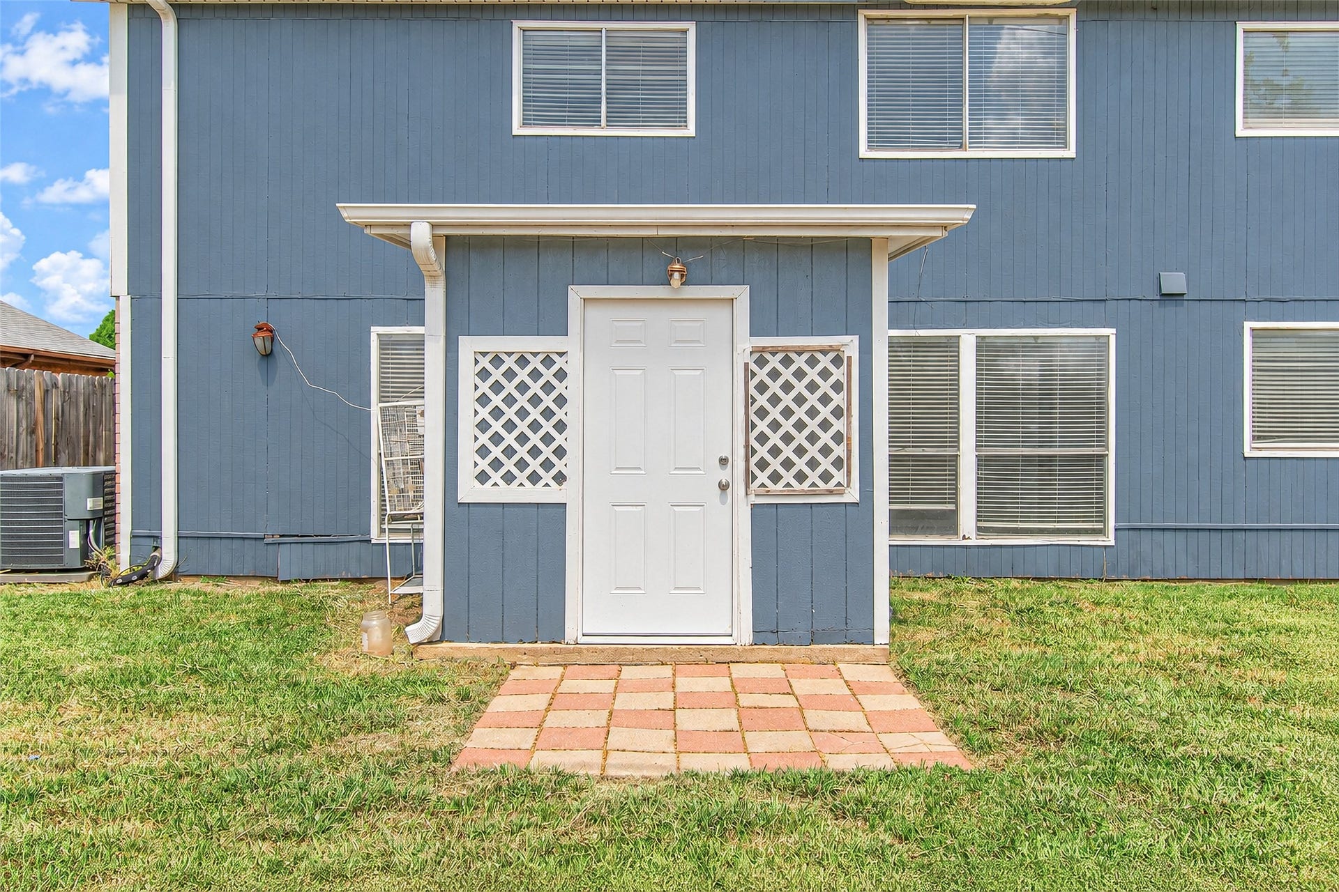 12027 Huntington Park Drive, Houston, TX 77099 Charming blue exterior with a welcoming side entrance and lattice accents, complemented by a neatly paved walkway and a well-maintained lawn.
