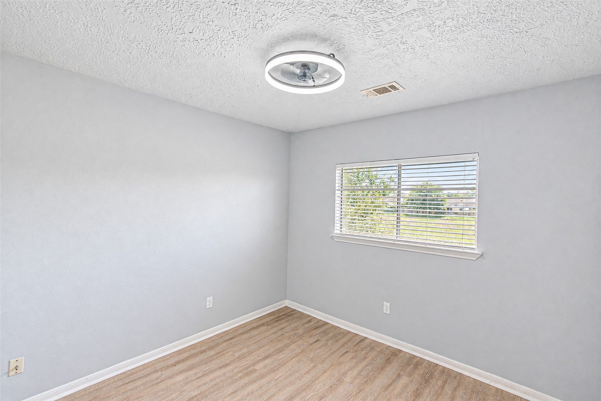 12027 Huntington Park Drive, Houston, TX 77099 Bright and airy room featuring fresh neutral walls, a modern light fixture, and a large window offering natural light and views of the outdoors.