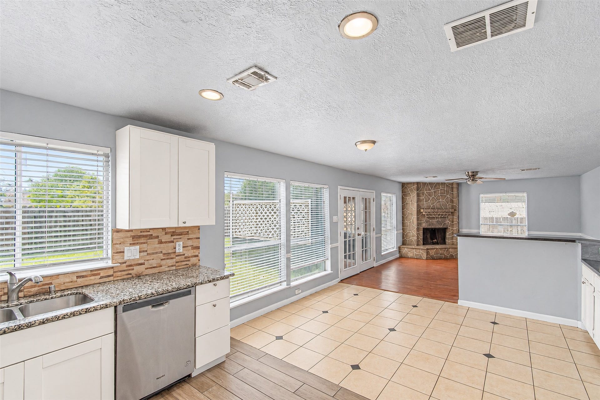 12027 Huntington Park Drive, Houston, TX 77099 Bright and spacious kitchen and living area featuring large windows, a cozy stone fireplace, modern cabinetry, and an open layout perfect for entertaining.