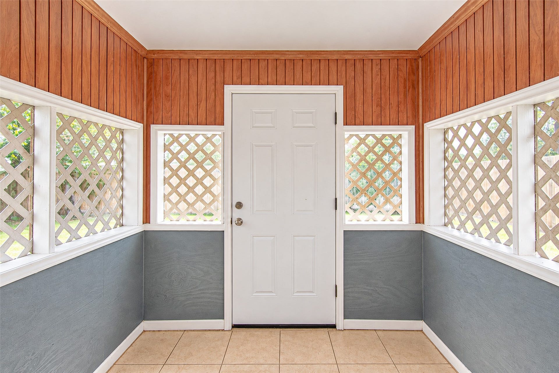 12027 Huntington Park Drive, Houston, TX 77099 Charming entryway with warm wood paneling and lattice windows, creating an inviting and cozy atmosphere.