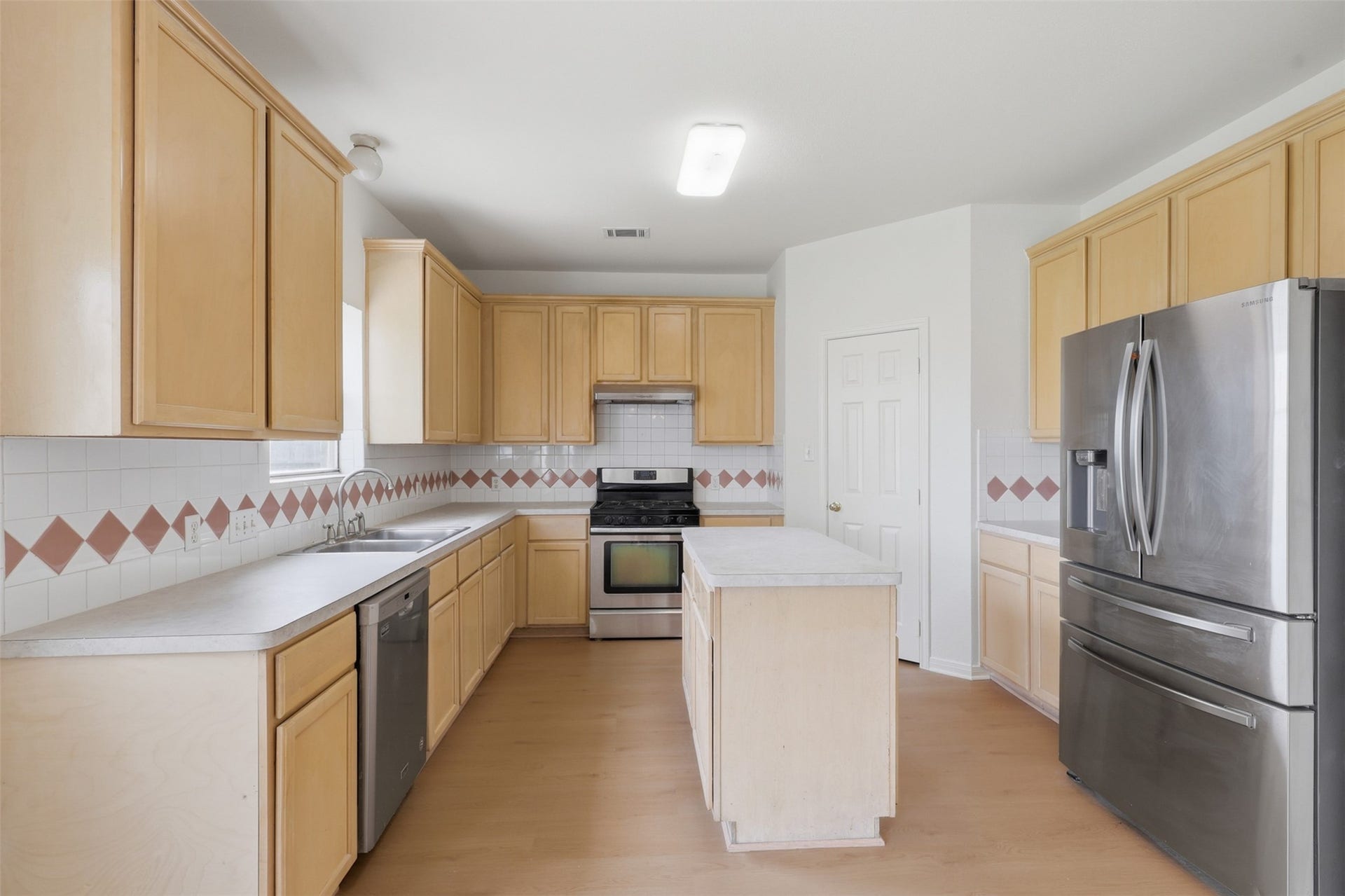 16622 Stoneside Drive, Houston, TX 77095 A centrally positioned island anchors the cooking space, which offers abundant blonde cabinetry and a diamond-patterned tile backsplash.