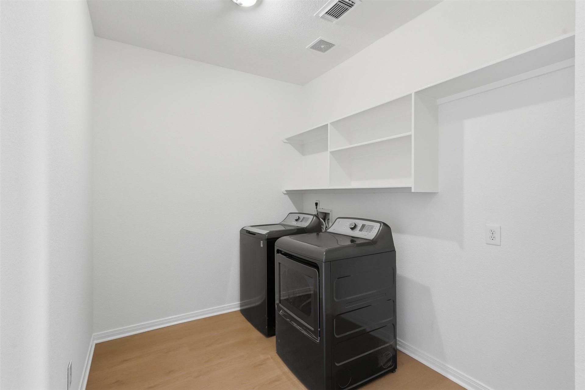 16622 Stoneside Drive, Houston, TX 77095 A practical laundry room features functional storage shelving mounted above durable wood-look flooring.