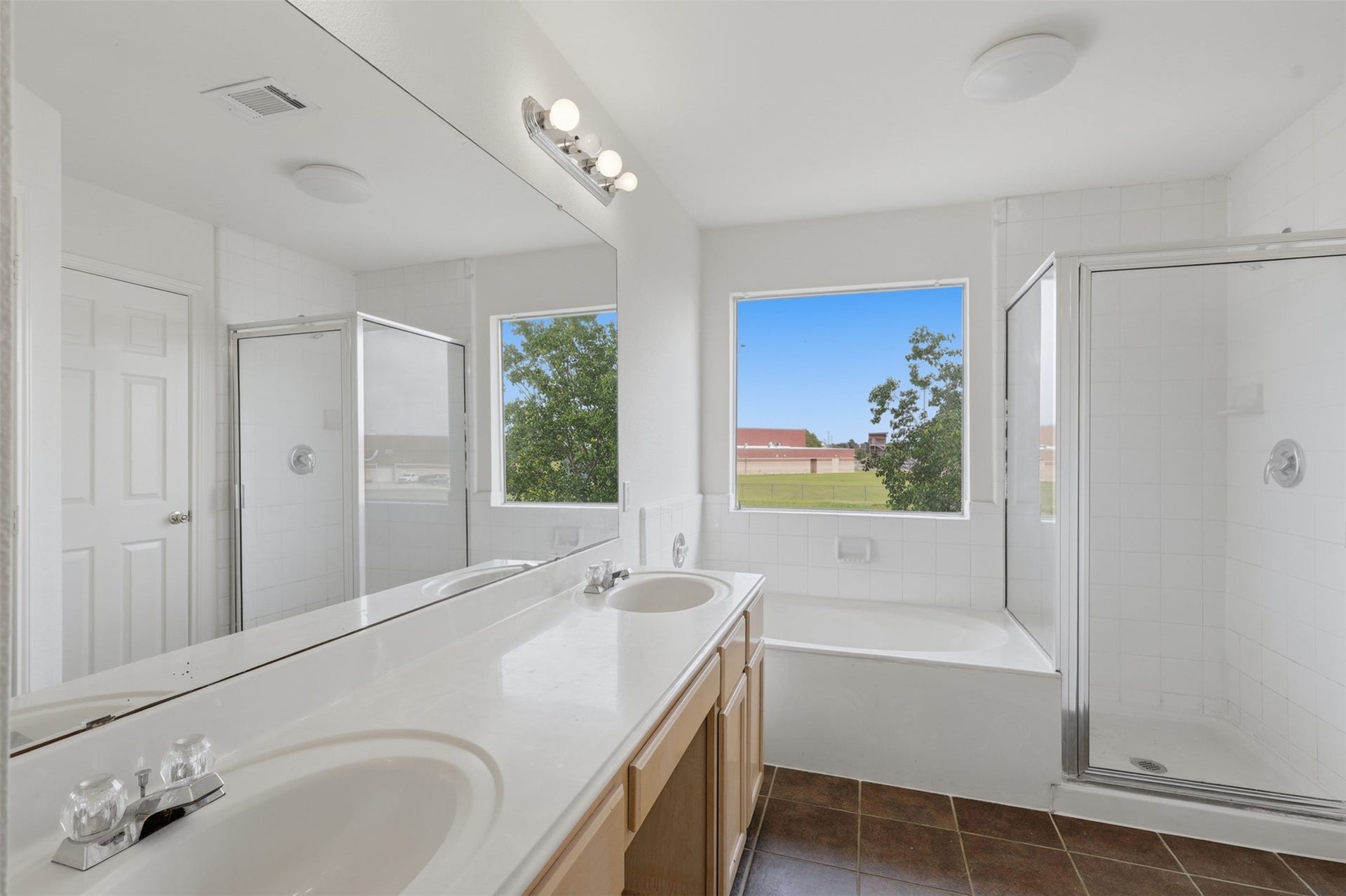 16622 Stoneside Drive, Houston, TX 77095 The full primary bathroom is equipped with an extended dual-sink vanity, a dedicated soaking tub under a bright window, and a separate glass-enclosed shower stall.