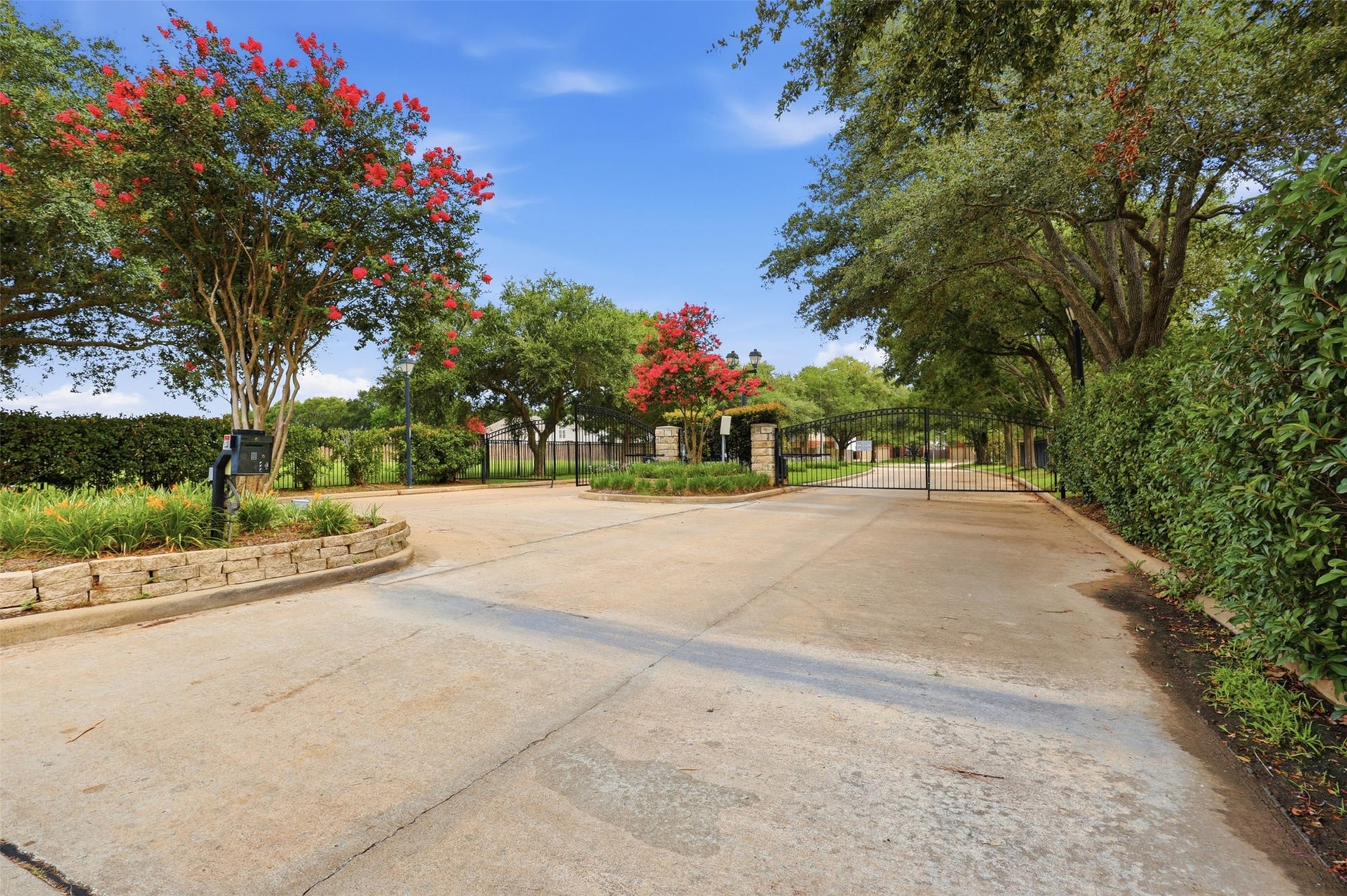 16622 Stoneside Drive, Houston, TX 77095 A gated entrance with an ornate iron security gate, stone pillars, and manicured hedges creates a secure and welcoming entrance to the neighborhood.