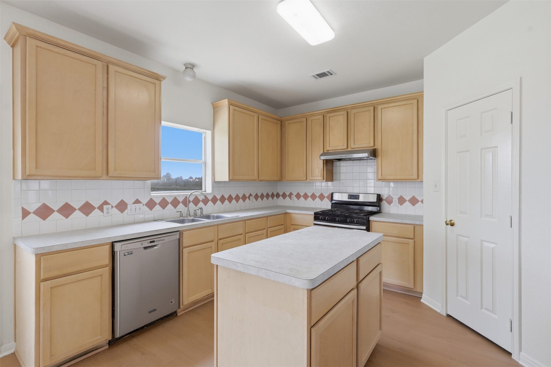 16622 Stoneside Drive, Houston, TX 77095 A square window frames outdoor views directly over the stainless steel double-basin sink and smooth laminate countertops.