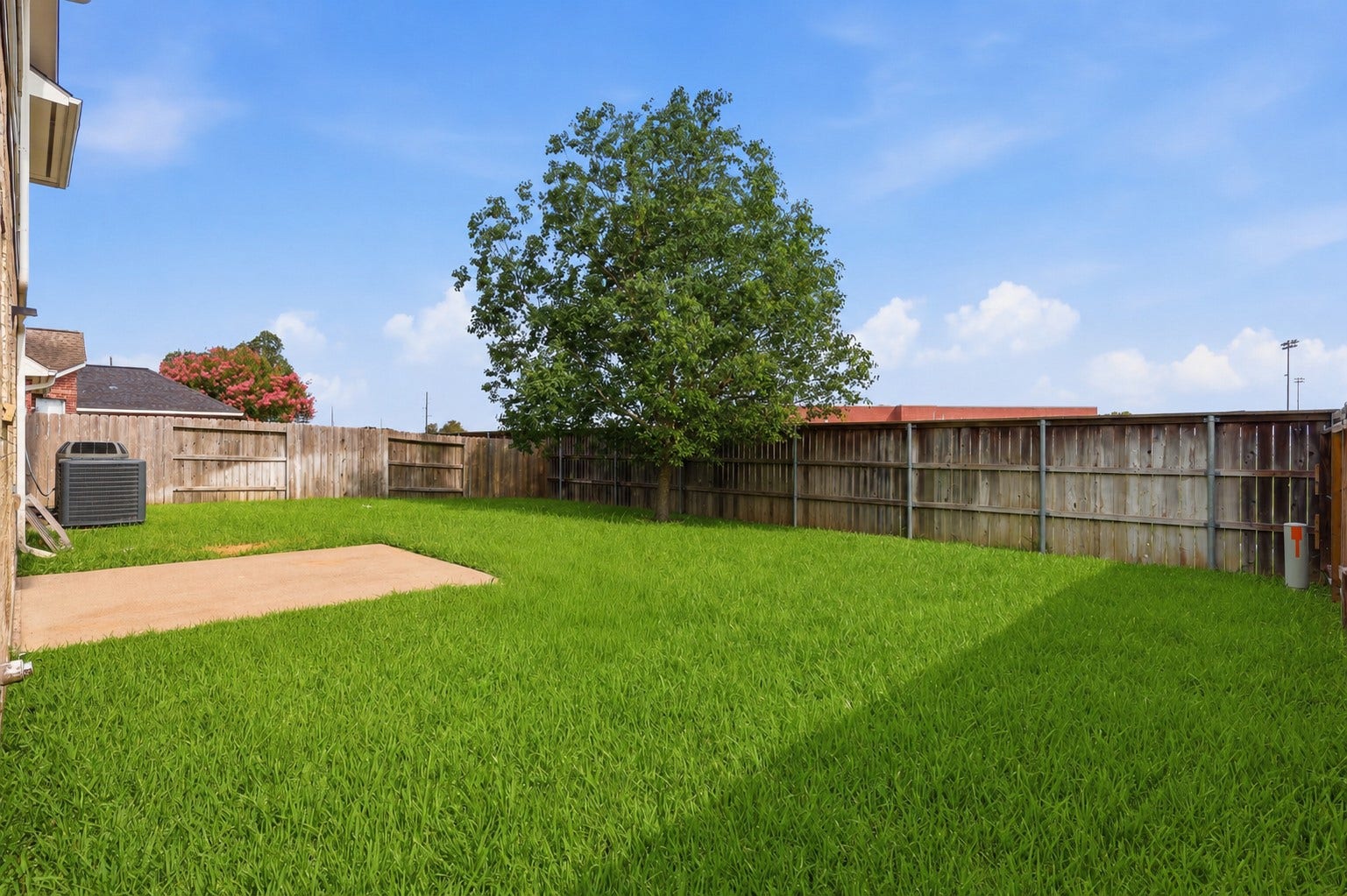 16622 Stoneside Drive, Houston, TX 77095 A wooden privacy fence encloses the grassy backyard, which includes a concrete patio pad and a side-mounted cooling unit.