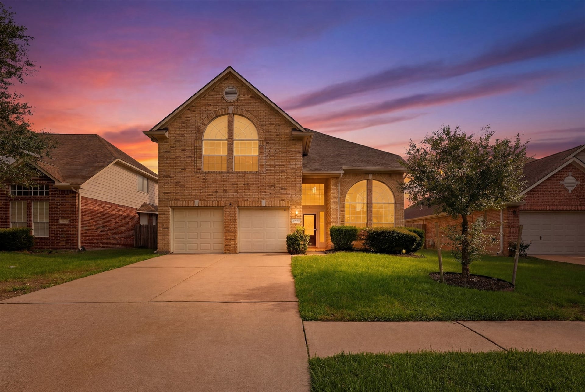 16622 Stoneside Drive, Houston, TX 77095 The timeless brick facade boasts dual garage bays and a striking front elevation illuminated against the evening sky.