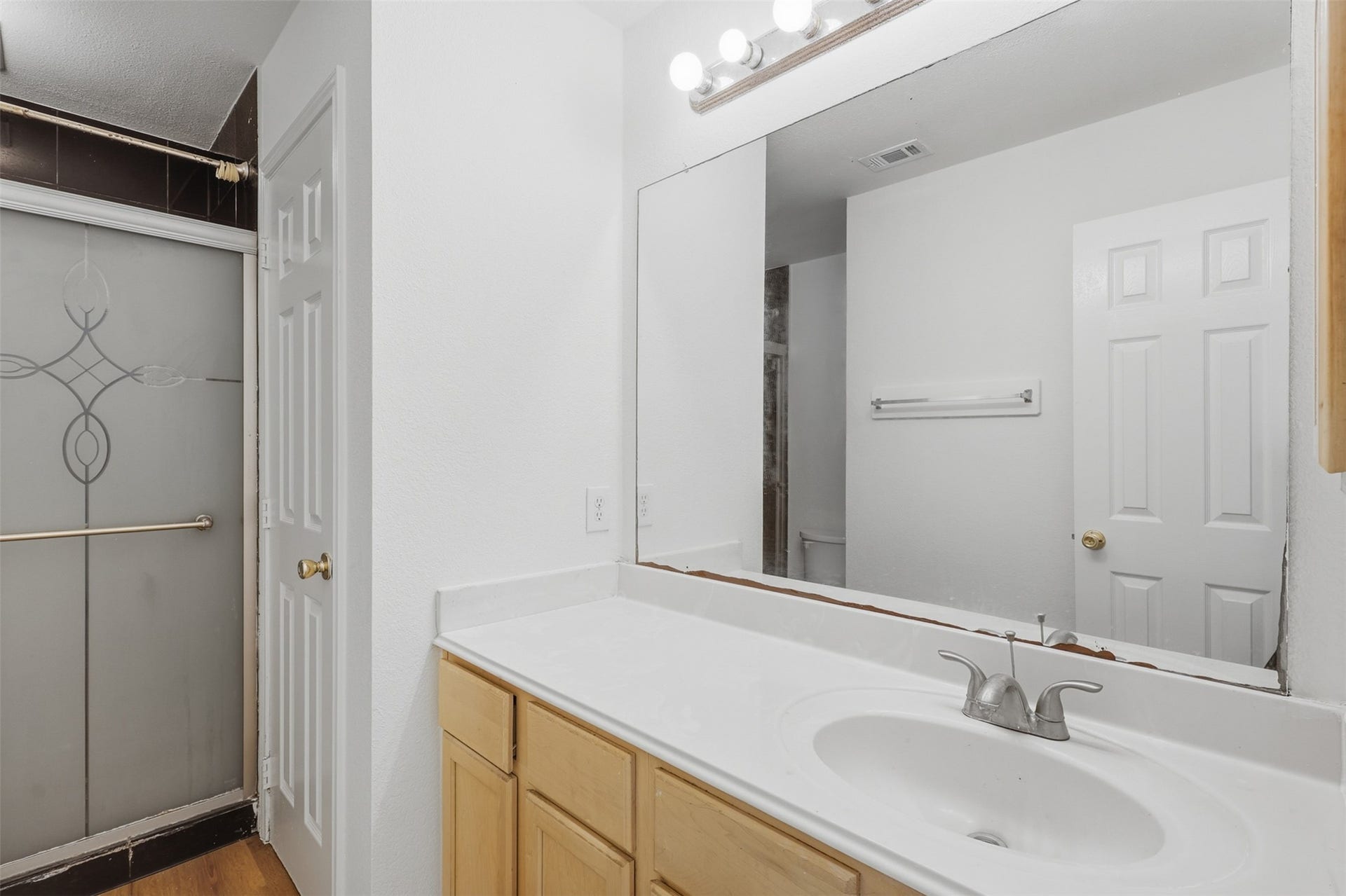 16622 Stoneside Drive, Houston, TX 77095 A single-sink vanity with light wood cabinetry, a wide mirror, and vanity lighting complements the enclosed bathing area.
