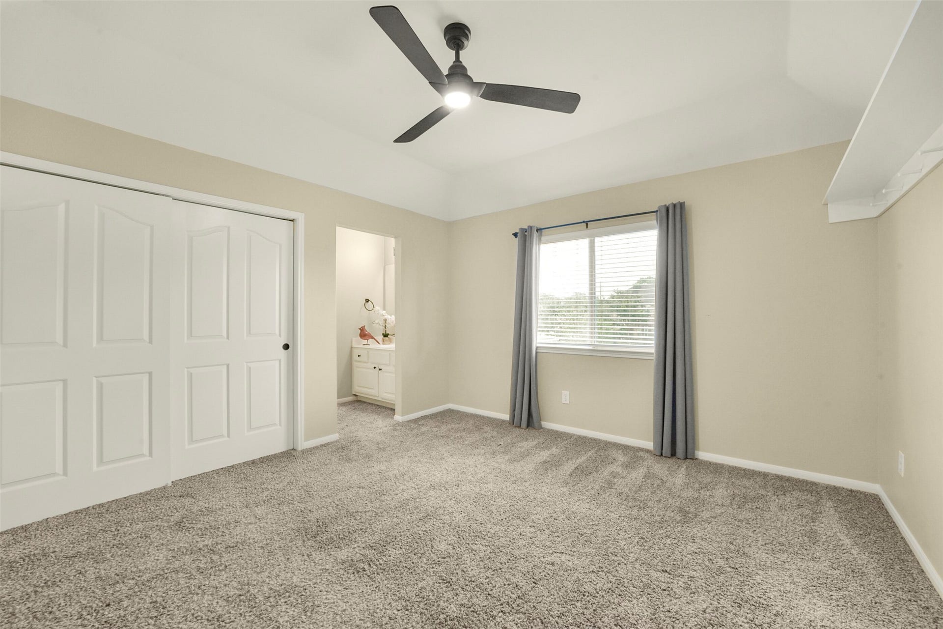 15730 Lake Loop Drive, Cypress, TX 77433 Spacious bedroom with plush carpeting, a modern ceiling fan, and ample natural light from a large window. Includes a convenient Jack and Jill bathroom and a double-door closet for ample storage.