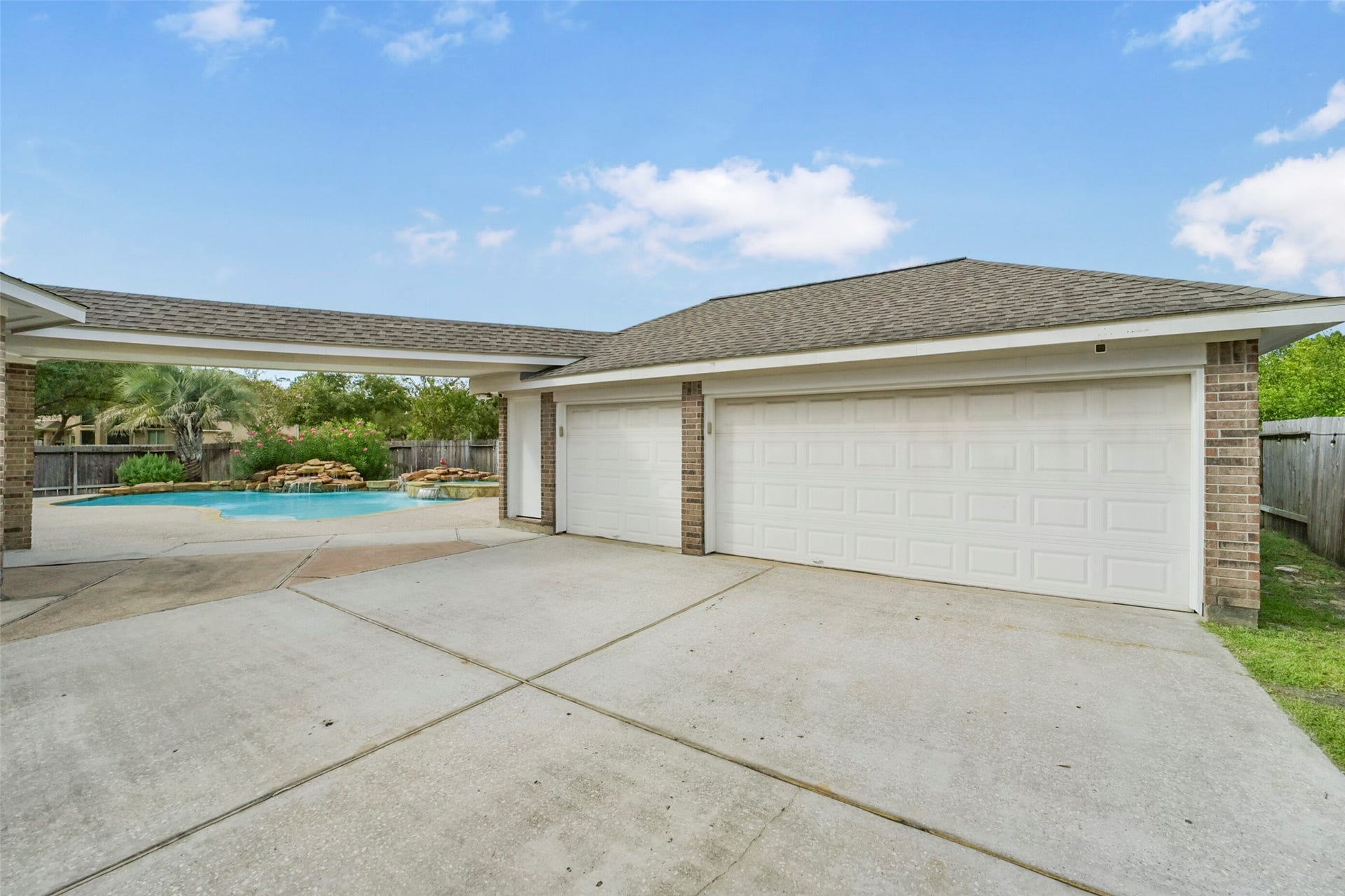 15730 Lake Loop Drive, Cypress, TX 77433 Spacious driveway leads to a large three-car garage, with a glimpse of a refreshing backyard pool area perfect for relaxation.