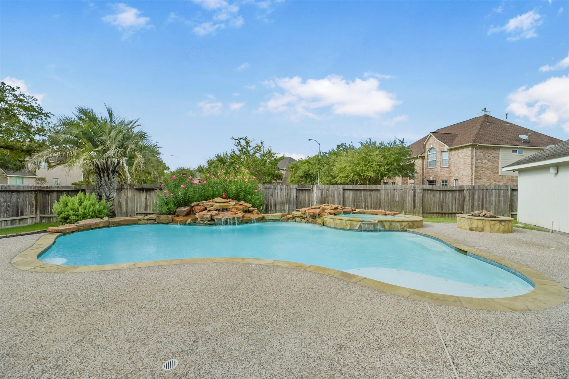 15730 Lake Loop Drive, Cypress, TX 77433 Enjoy a private oasis with this stunning backyard featuring a sparkling pool, soothing waterfall, and a cozy fire pit, all surrounded by lush greenery for ultimate relaxation.