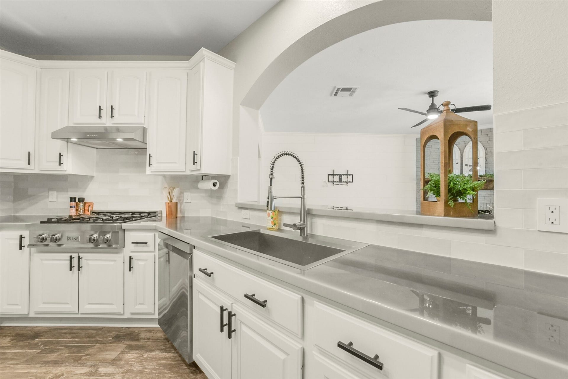 15730 Lake Loop Drive, Cypress, TX 77433 Modern kitchen featuring sleek stainless steel appliances, elegant white cabinetry, and a spacious open layout with a stylish archway.