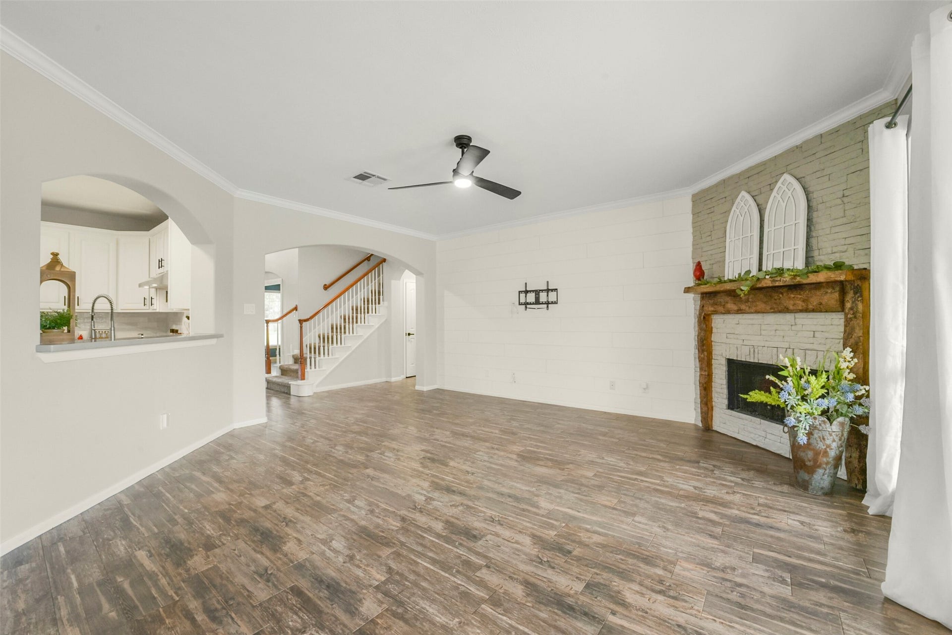 15730 Lake Loop Drive, Cypress, TX 77433 Spacious living area with elegant wood flooring, a charming brick fireplace, and abundant natural light from large windows overlooking the backyard.