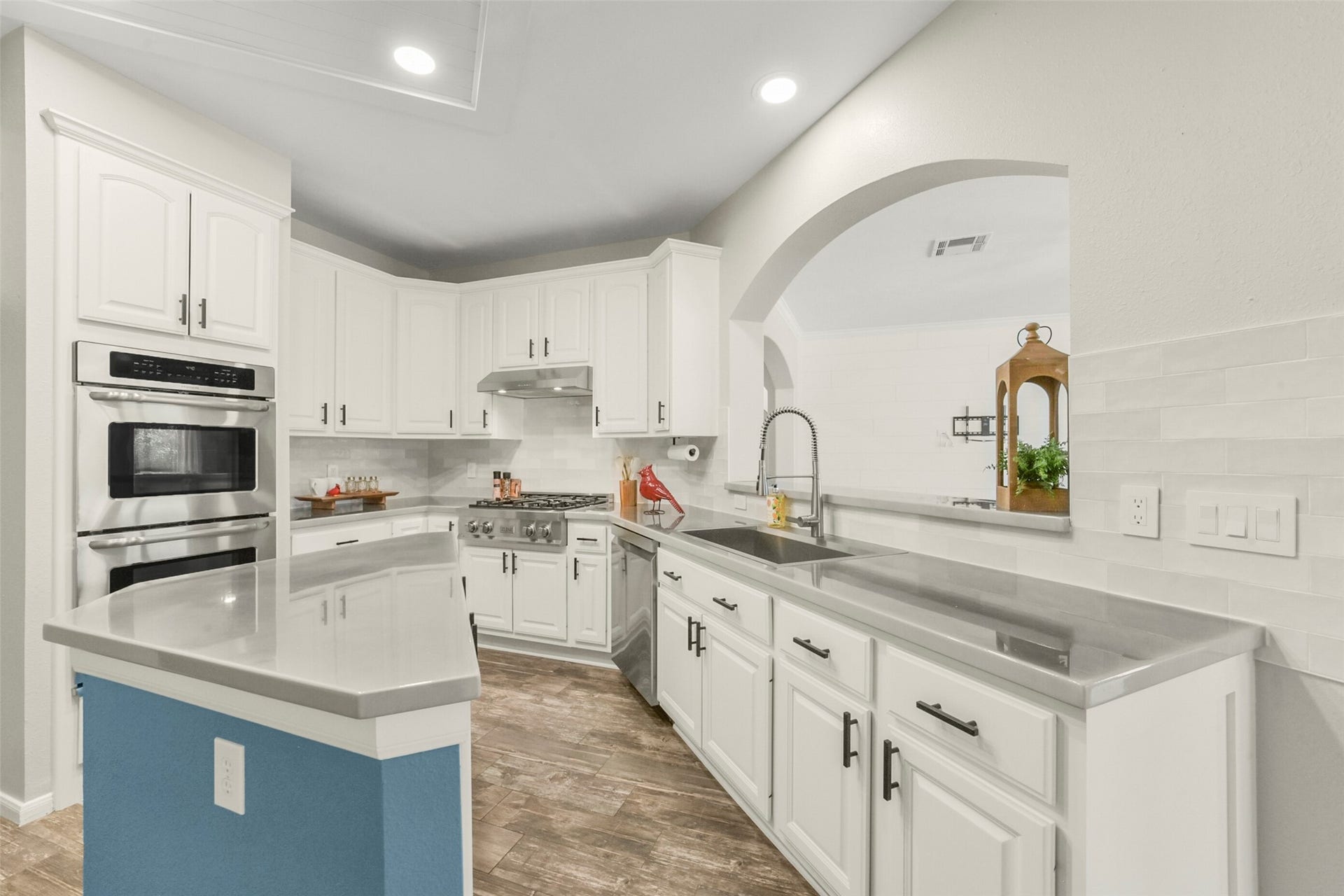 15730 Lake Loop Drive, Cypress, TX 77433 Bright and spacious kitchen featuring sleek stainless steel appliances, elegant white cabinetry, and a large island with ample counter space, all complemented by stylish wood flooring and recessed lighting.