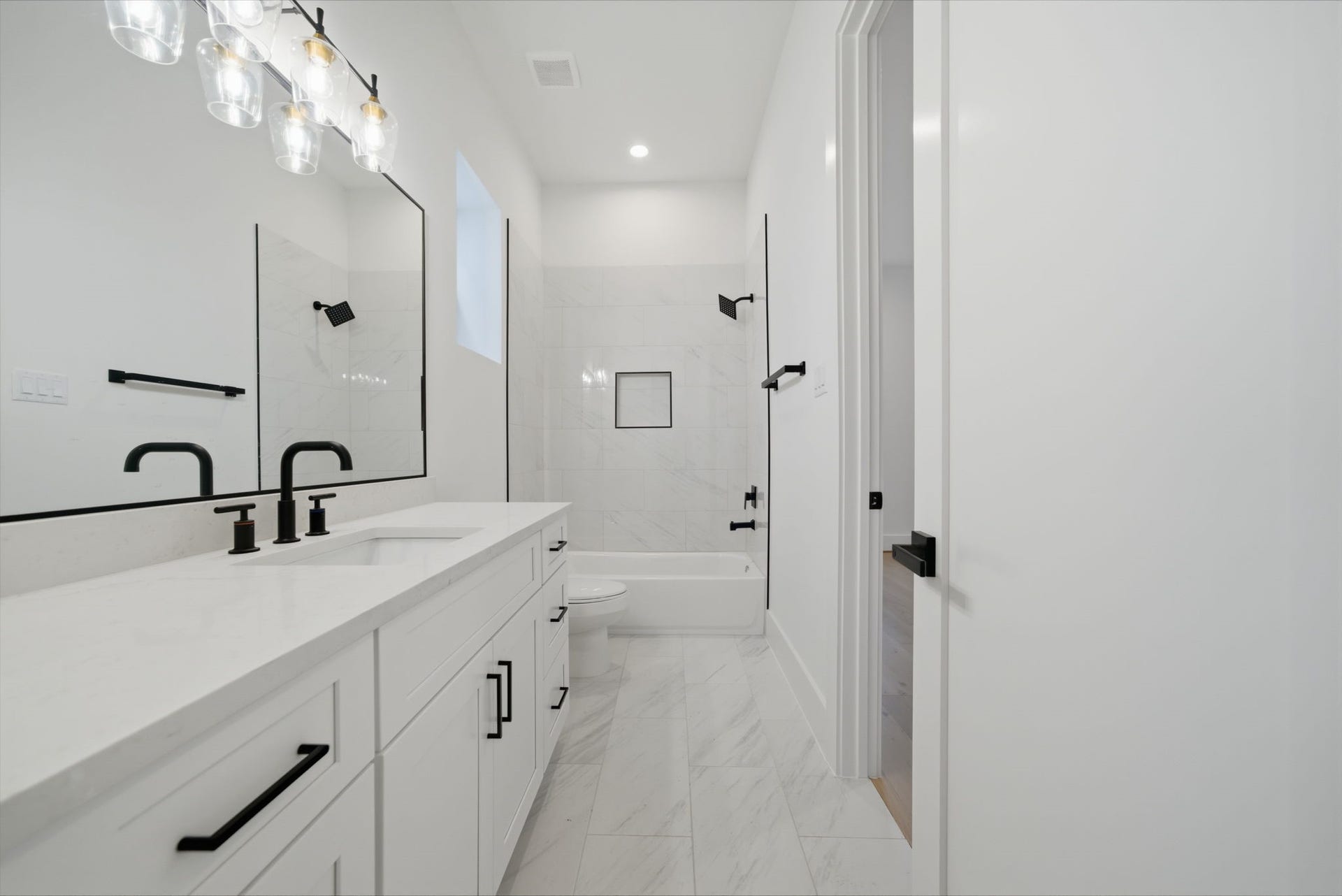 Guest bath #1 with quartz counters, black matte hardware, and plenty of storage and counter space. (Photos are of a previously completed home. Finishes are subject to change.)