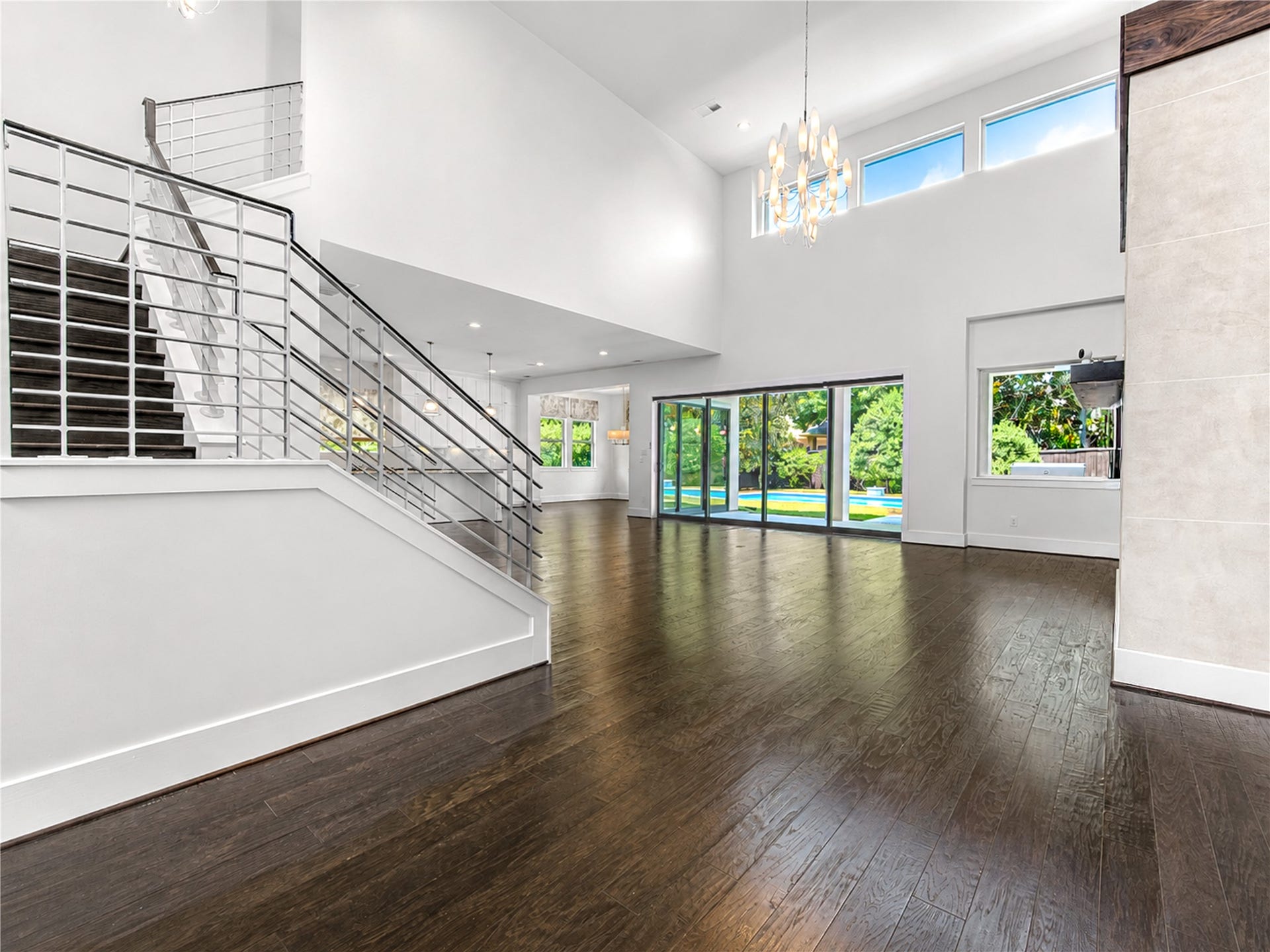 A dramatic staircase, sculptural lighting and expansive walls of glass define the grand living space, perfectly framing views of the backyard oasis.