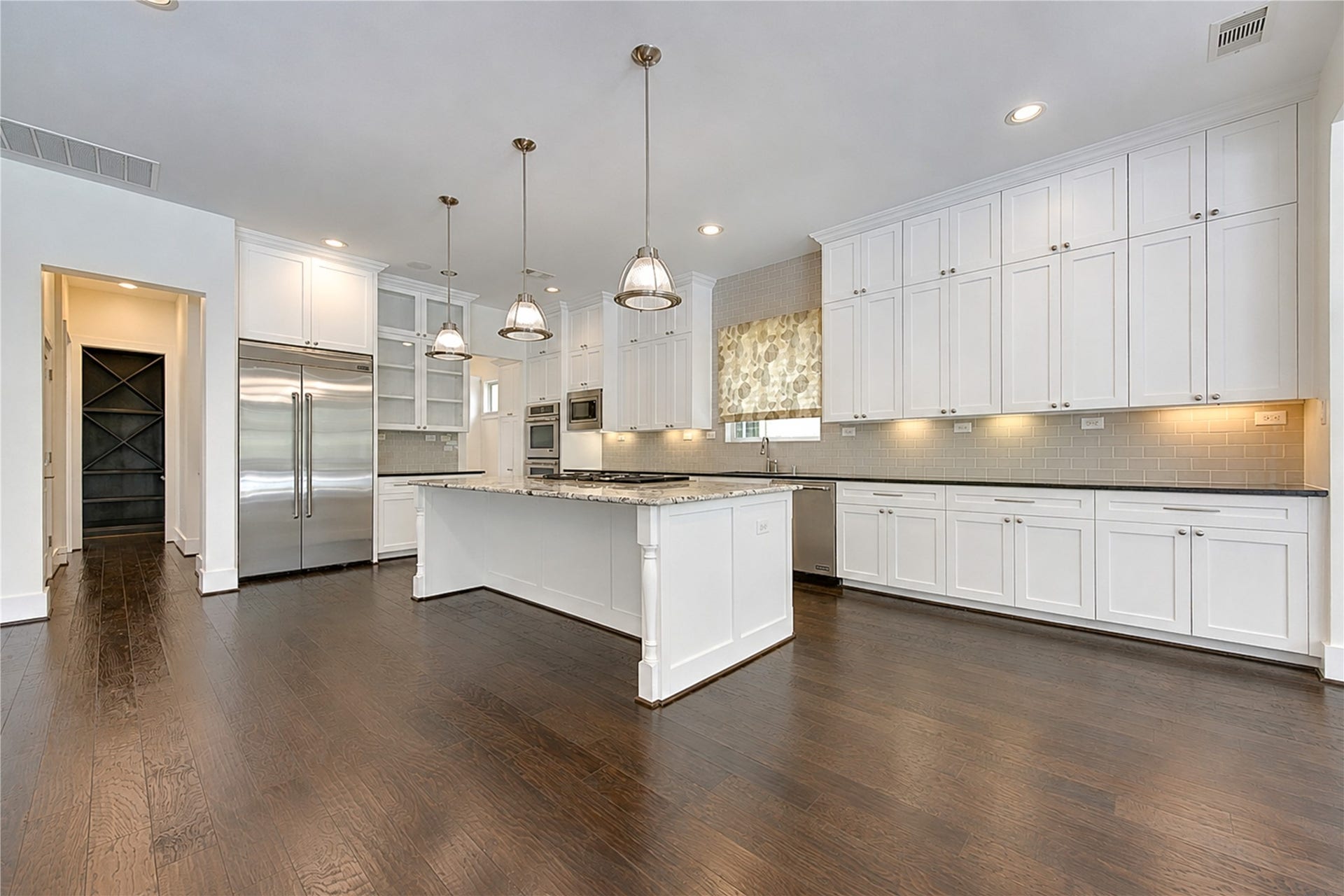 Wall-to wall cabinetry, expansive countertops and a built-in stainless steel refrigerator provide exceptional storage and prep space in this beautiful appointed kitchen.