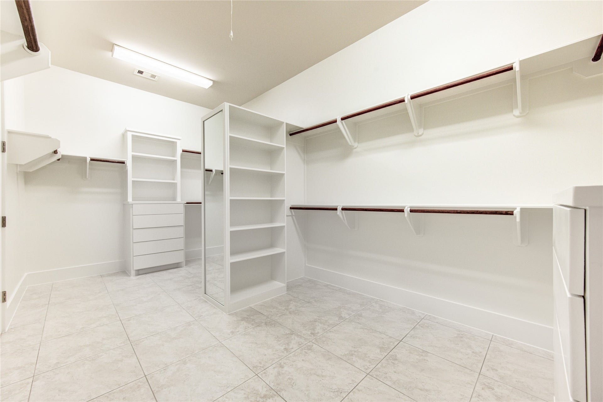 The expansive walk-in closet offers extensive hanging space, built-in shelving and drawers, providing room for an impeccably organized wardrobe.