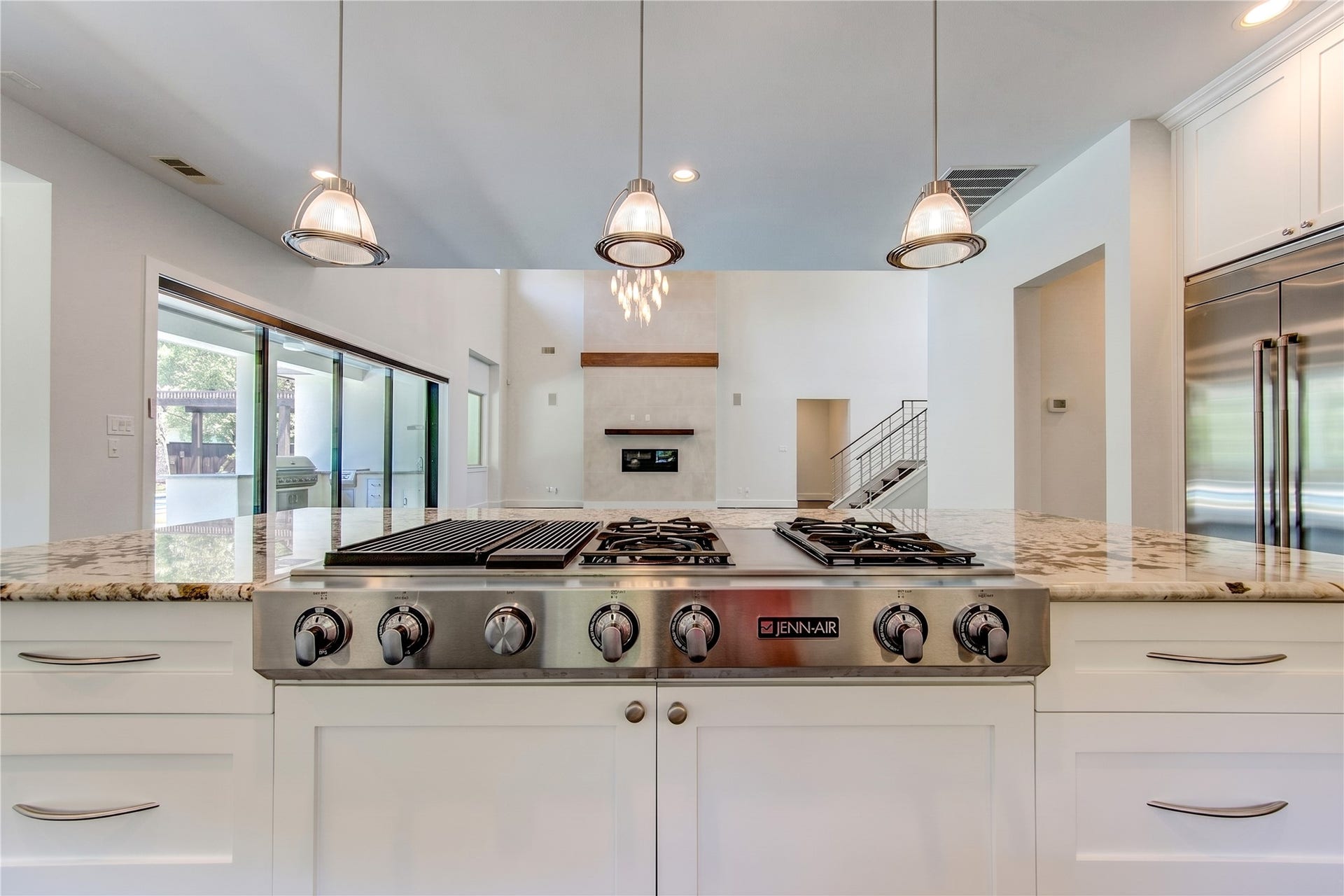 A professional-style JennAir gas cooktop anchors the oversized island, allowing the home chef to stay connected to guest and the surrounding living spaces.