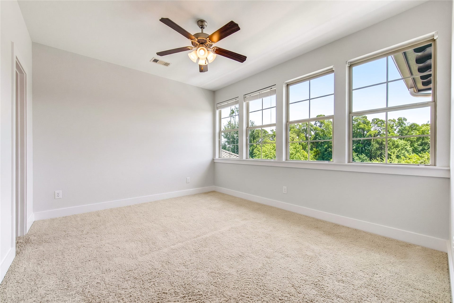 One of the three upstairs secondary bedrooms, this light-filled retreat feautures a wall of windows framing peaceful lake views and direct access to a full bath.