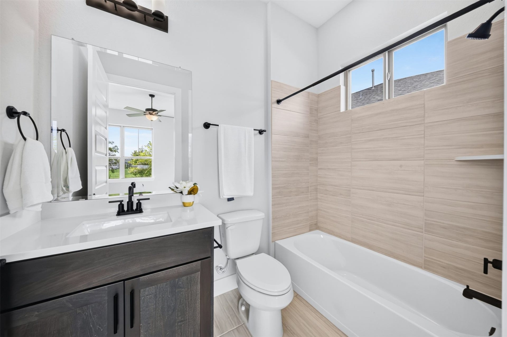 32510 Ebony Jewelwing Court, Fulshear, TX 77441 Secondary Bathroom Bright full bath featuring a tub/shower combination with modern tile surround, quartz-style vanity, black fixtures, and natural light.