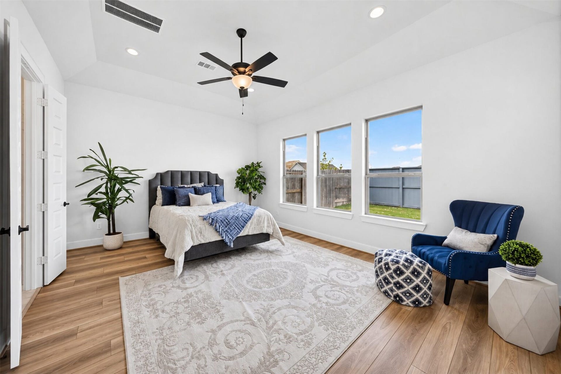 32510 Ebony Jewelwing Court, Fulshear, TX 77441 Primary Bedroom: Spacious primary retreat features a high ceiling, multiple windows, warm flooring, and ample room for additional seating.