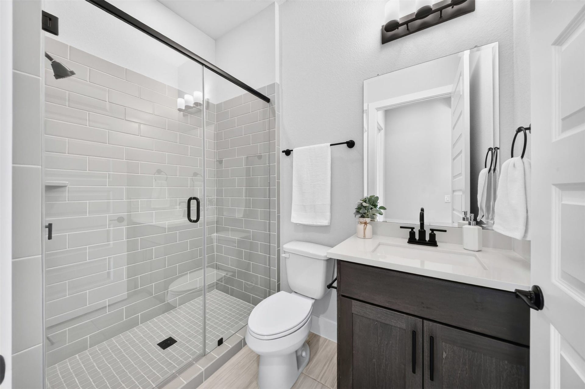 32510 Ebony Jewelwing Court, Fulshear, TX 77441 Full Bathroom Crisp, modern bath featuring a glass-enclosed tiled shower, quartz-style countertop, dark cabinetry, and sleek black fixtures.