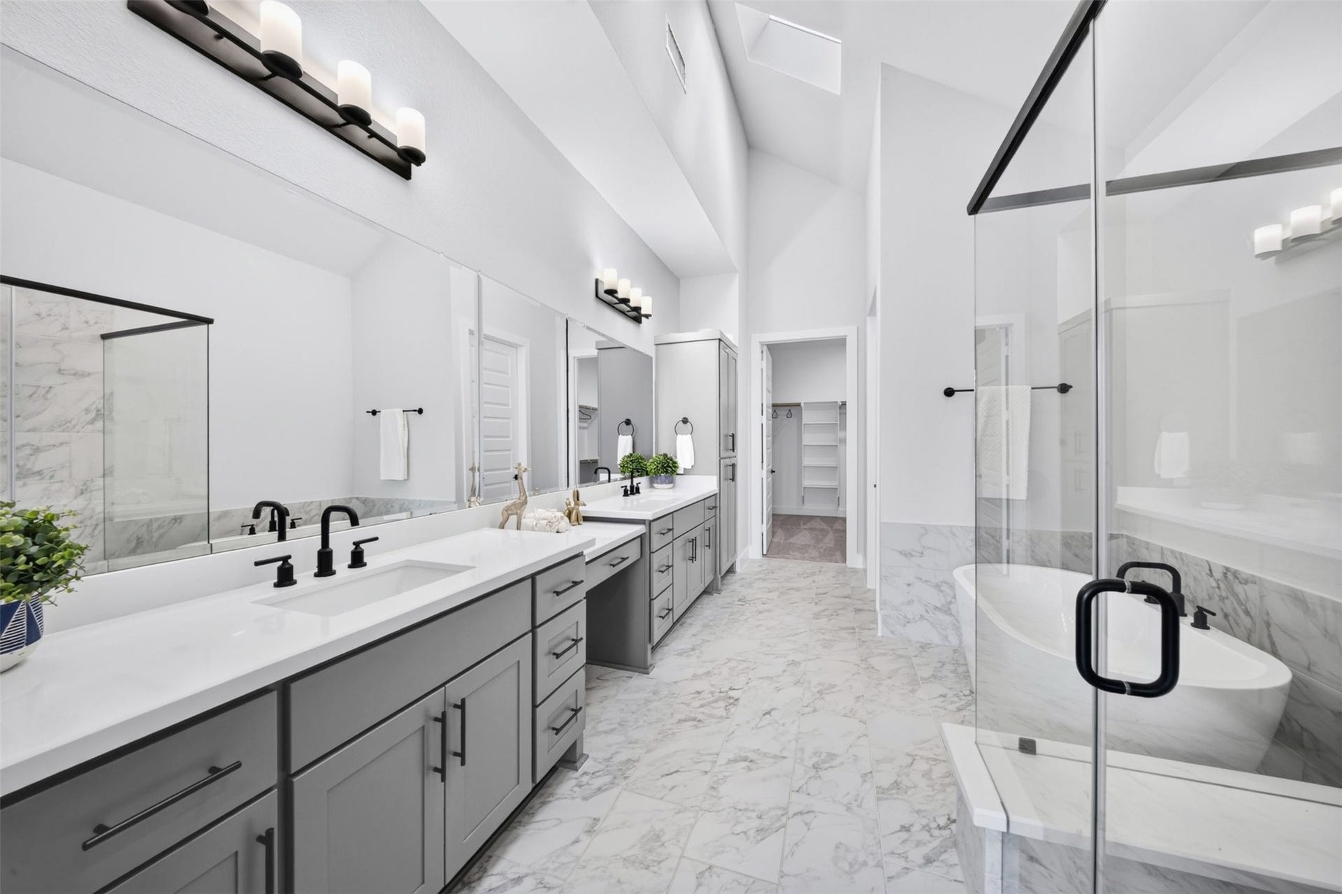 32510 Ebony Jewelwing Court, Fulshear, TX 77441 Primary Bathroom: Spa-inspired primary bath featuring dual vanities, expansive mirrors, sleek black fixtures, freestanding soaking tub, glass-enclosed shower, and beautiful marble-look finishes.