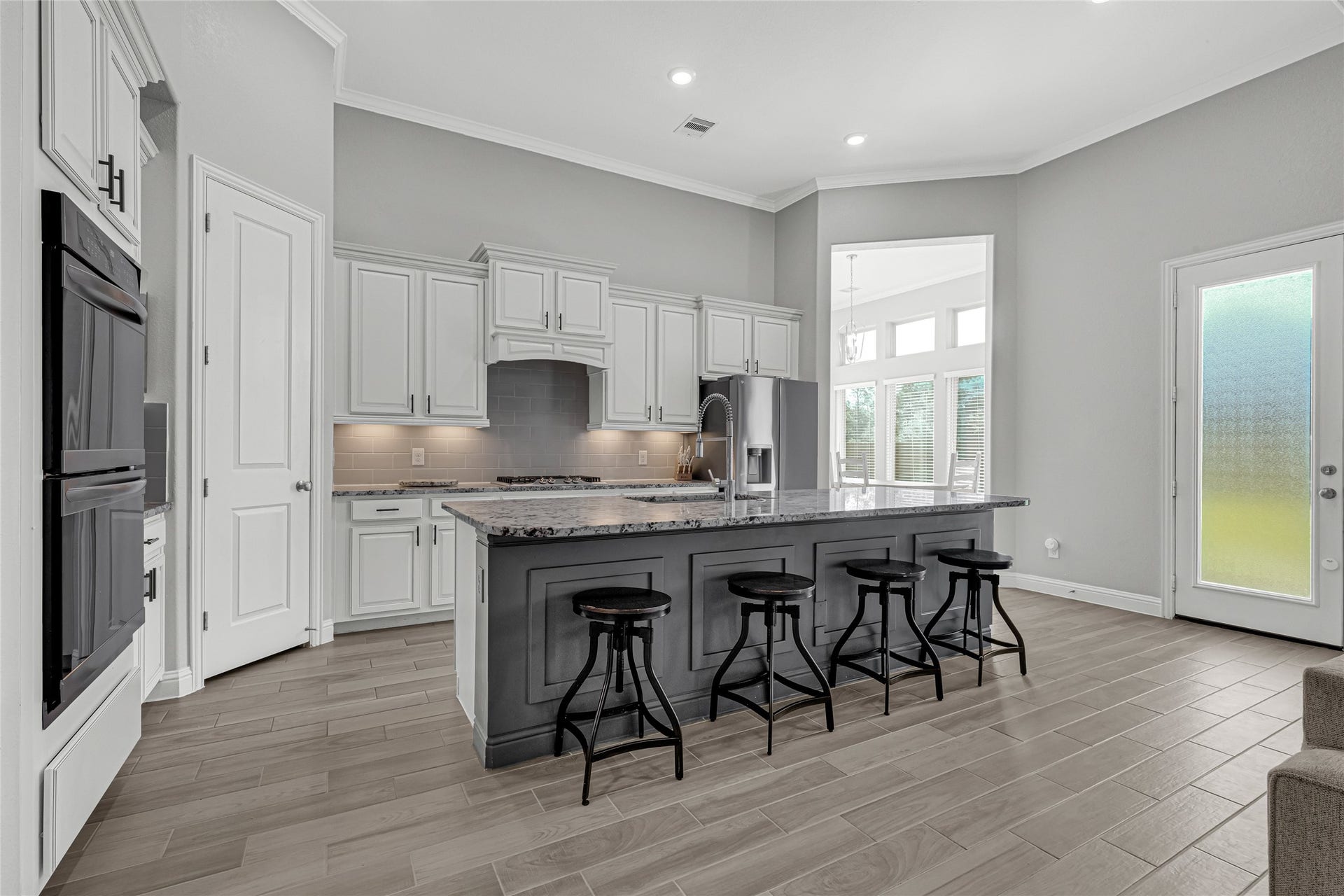 6023 Verde Place Lane, Katy, TX 77493 A kitchen with an island, gas cooktop, double oven built-in, a double size and extra deep sink, granite countertops, tall white kitchen cabintes, under cablnets lighting