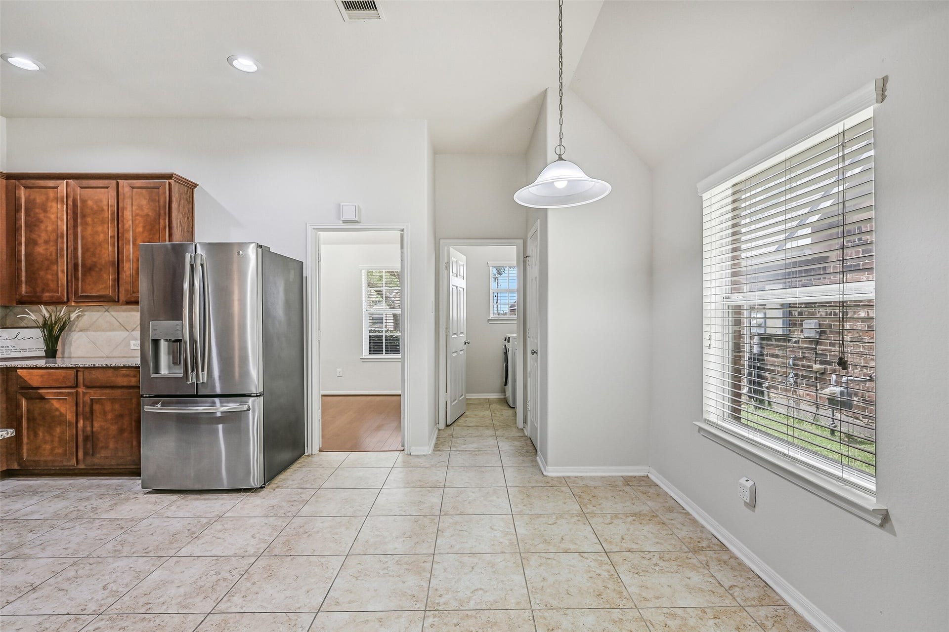 318 Lake Line Drive, Alvin, TX 77511 Natural light fills the breakfast area through a large window with 2" blinds, while tile flooring continues into the adjoining kitchen and utility area for a practical, easy-maintenance layout.