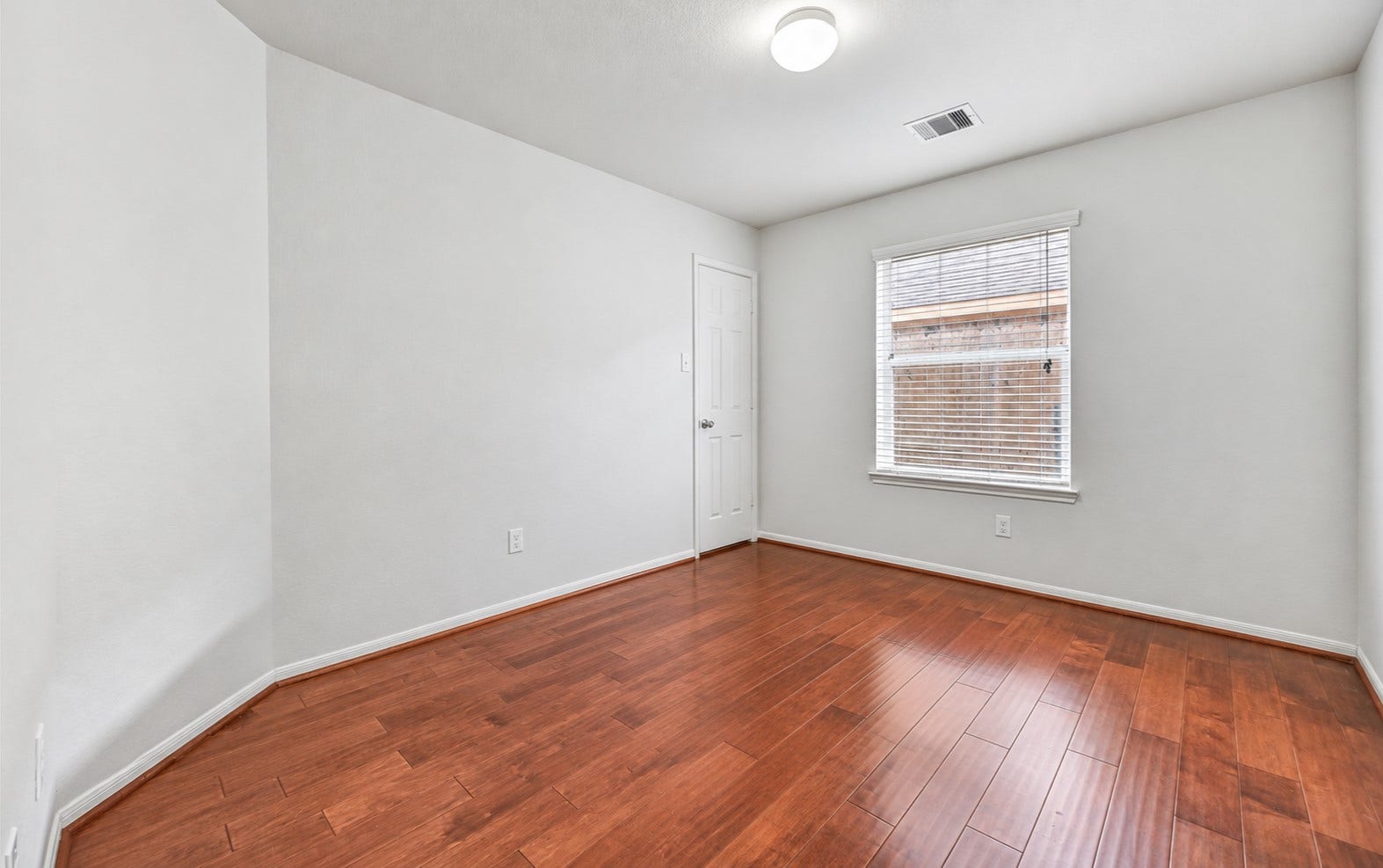 318 Lake Line Drive, Alvin, TX 77511 One of three secondary bedrooms offers fresh neutral paint, warm wood flooring, a large window with 2" blinds & a generous walk-in closet, continuing the home's clean, move-in ready feel.