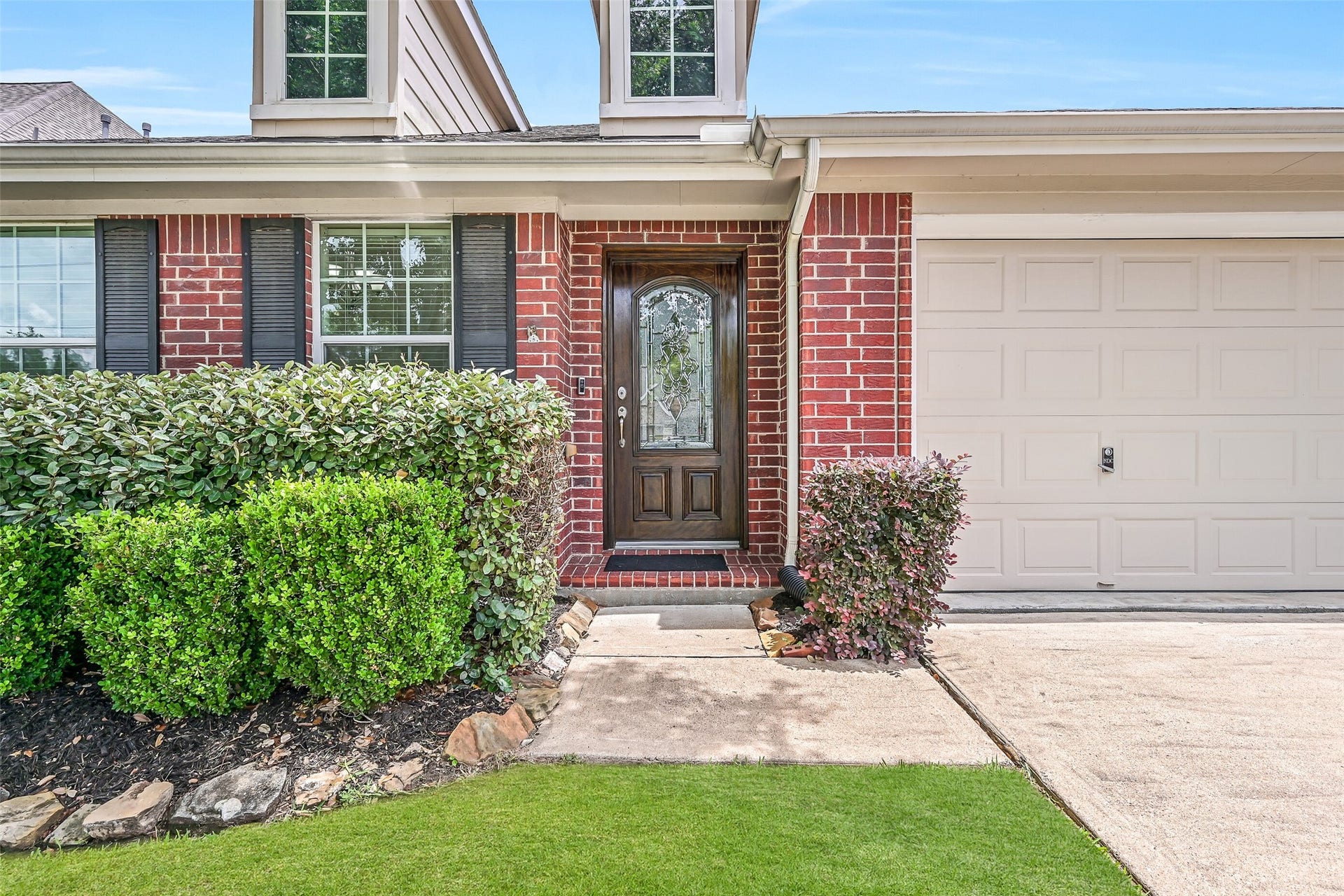 318 Lake Line Drive, Alvin, TX 77511 A closer look at the welcoming front entrance showcases manicured landscaping, classic brick exterior & a handsome wood front door with decorative glass, providing a beautiful introduction to this well-maintained home.