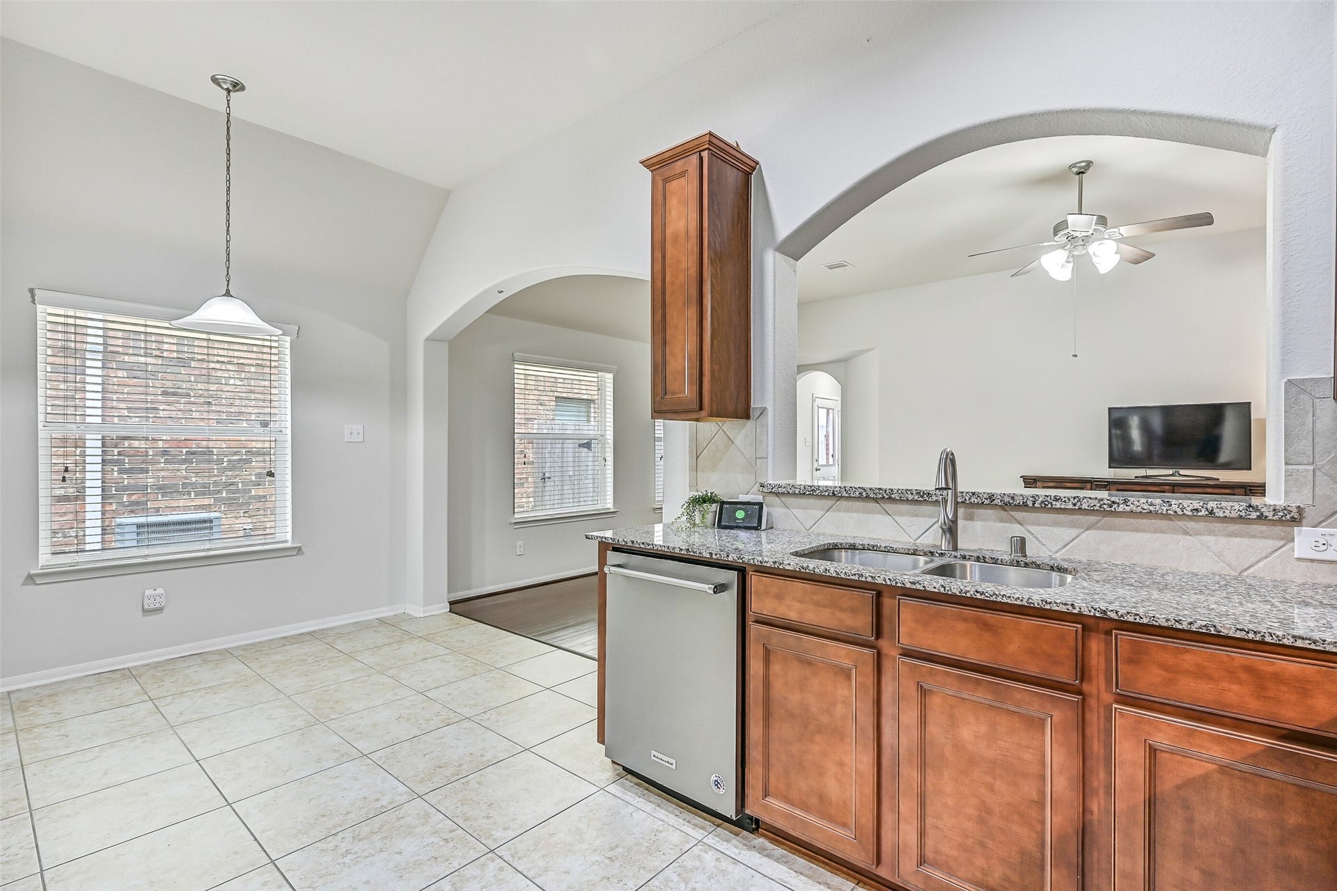 318 Lake Line Drive, Alvin, TX 77511 Looking from the kitchen toward the breakfast area, granite counters and a raised serving bar overlook the family room, creating an open layout that keeps the kitchen connected to both dining and living spaces.