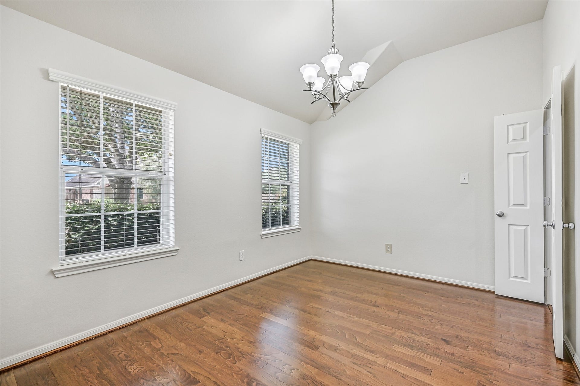 318 Lake Line Drive, Alvin, TX 77511 A second view of the light-filled dining room highlights dual windows with 2" blinds, beautiful wood flooring & the soaring vaulted ceiling, offering generous space for both everyday meals and special gatherings.