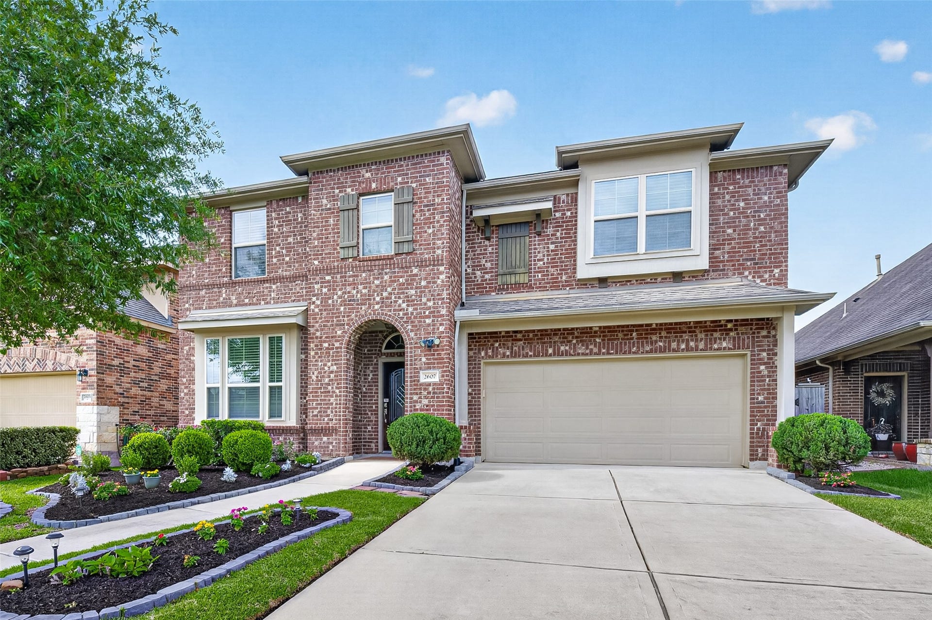 2607 River Run Road, Missouri City, TX 77459 This is a two-story brick home with a double garage. The front features a well-maintained garden, manicured shrubs, and a tidy walkway leading to the entrance. The large windows and contemporary design add to its curb appeal.