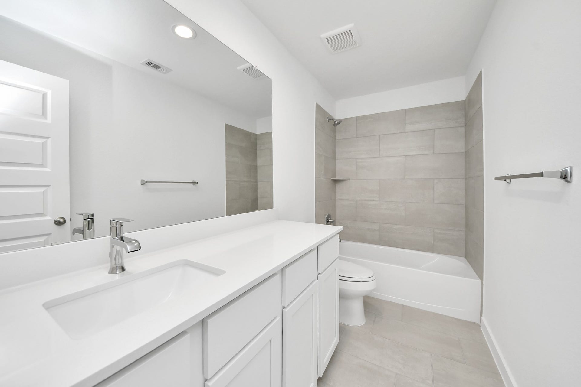 Secondary bath features tile flooring, bath/shower combo with tile surround, light stained wood cabinets, beautiful light countertop. Sample photo of completed home with similar floor plan. Actual colors and selections may vary.