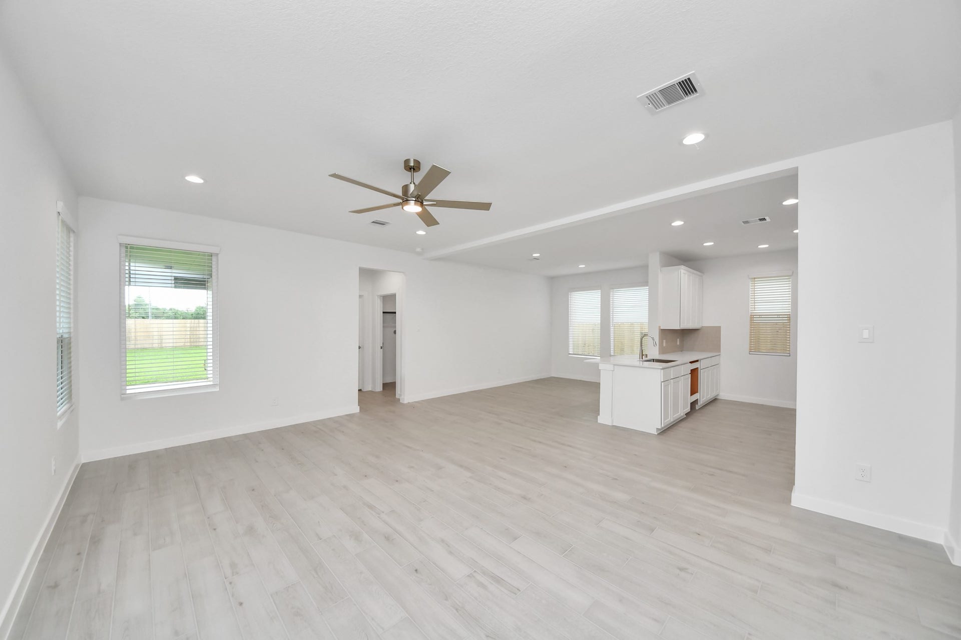 Welcome family and guests to your charming living room! With its high ceilings, recessed lighting, ceiling fan, custom paint, beautiful flooring, and large windows that let in abundant natural light, this room is perfect for gatherings. Sample photo of completed home with similar floor plan. Actual colors and selections may vary.