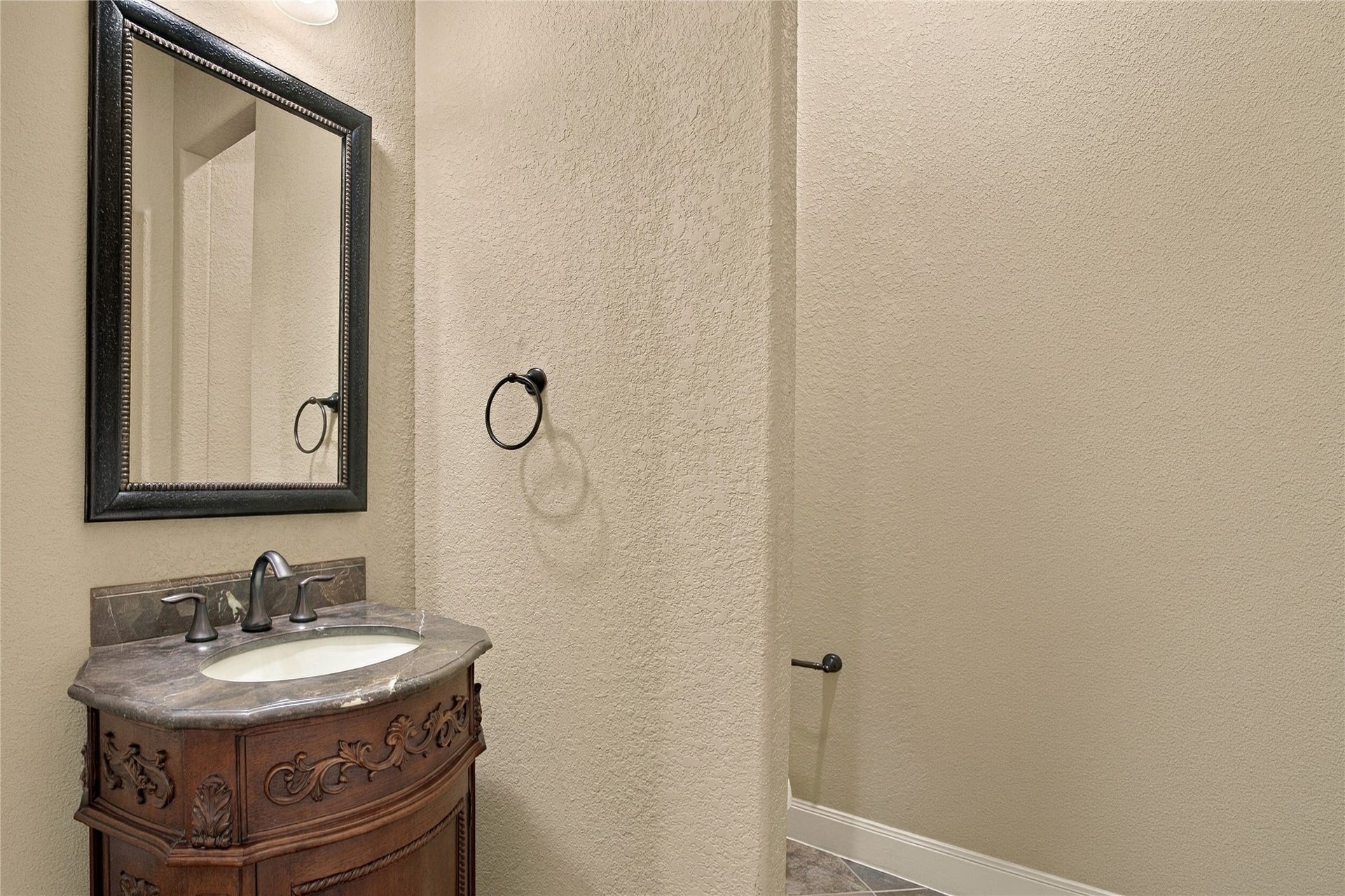 19215 Shady Blossom Drive, Cypress, TX 77433 Convenient downstairs half bathroom featuring a decorative vanity and framed mirror.