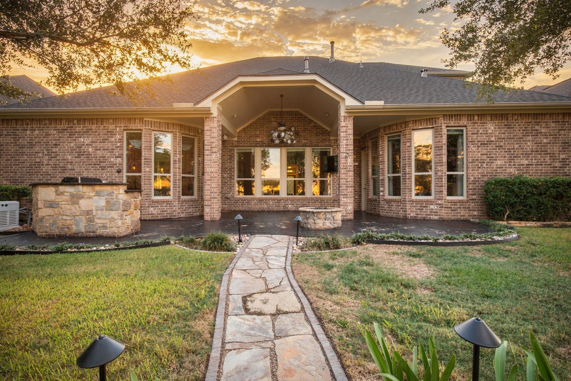 19215 Shady Blossom Drive, Cypress, TX 77433 Beautiful rear exterior showcasing the expansive covered patio, large windows, and landscaped backyard, all highlighted by gorgeous sunset views that create a truly breathtaking setting!