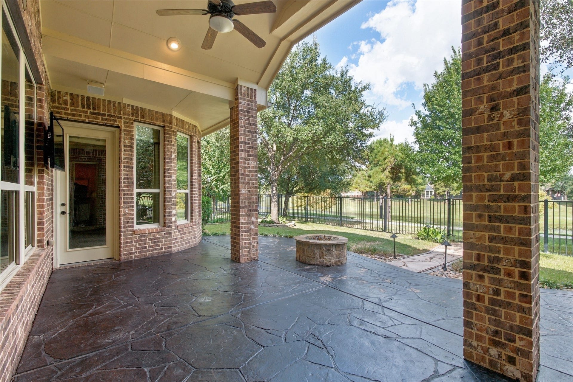 19215 Shady Blossom Drive, Cypress, TX 77433 Expansive covered patio featuring ceiling fans, outdoor speakers, and a gas fire pit. This inviting outdoor space is perfect for relaxing or entertaining while enjoying beautiful waterfront views.