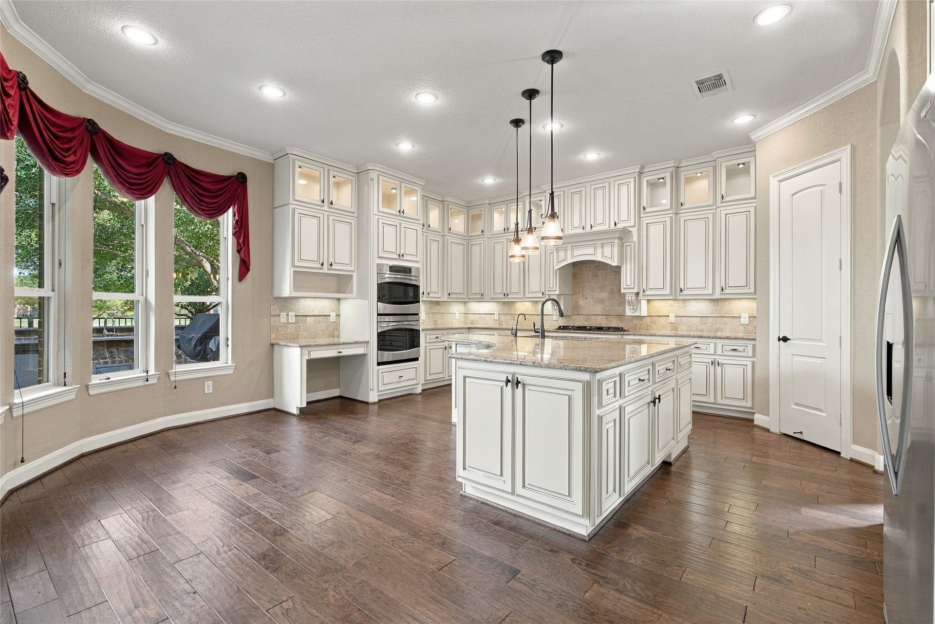 19215 Shady Blossom Drive, Cypress, TX 77433 Stunning kitchen featuring granite countertops, a spacious island, cabinetry extending to the ceiling, double ovens, and beautiful wood flooring.