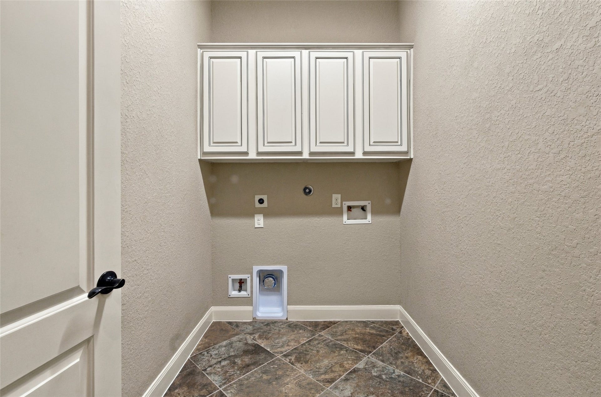 19215 Shady Blossom Drive, Cypress, TX 77433 Downstairs laundry room featuring overhead cabinetry and space for a washer and dryer.