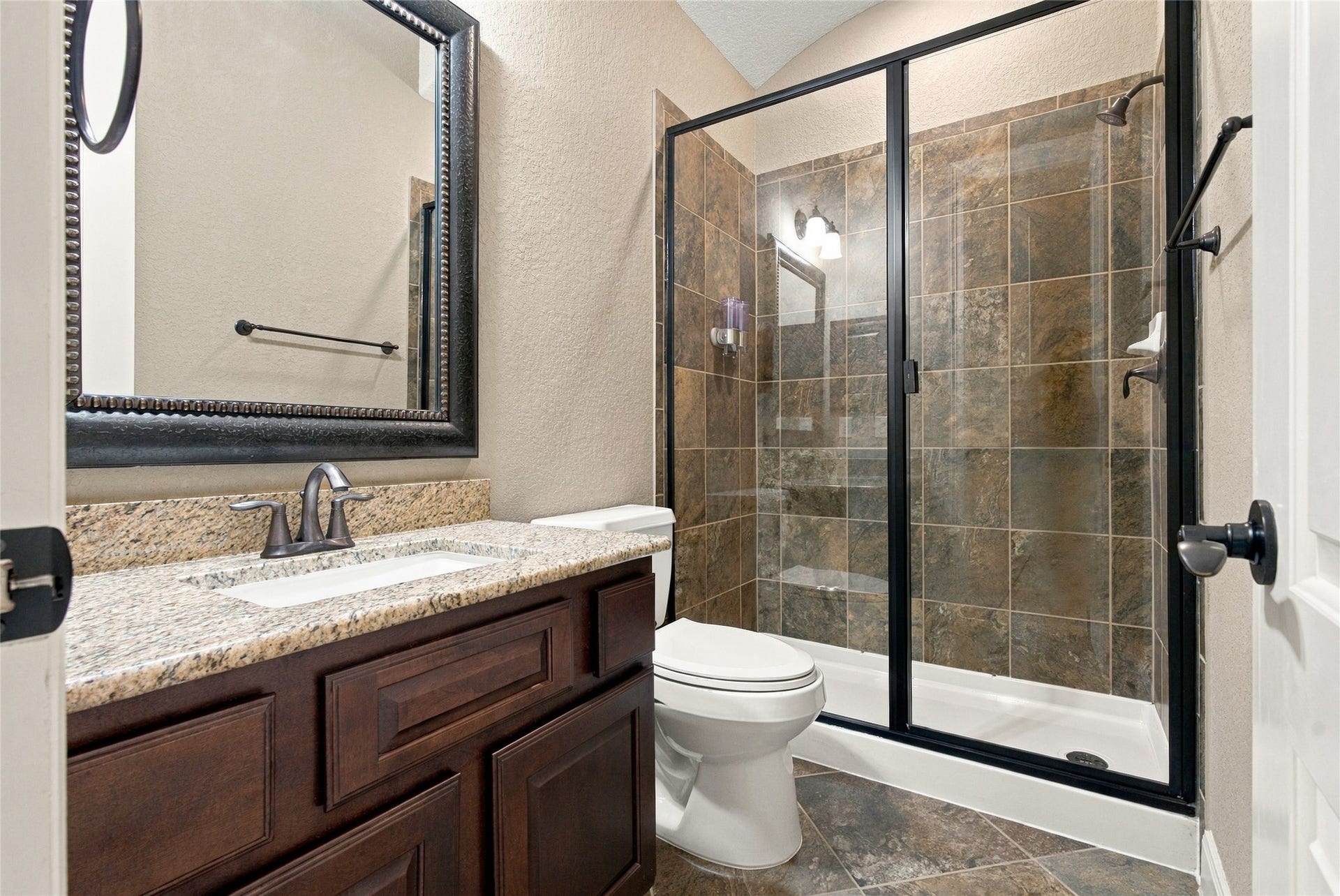 19215 Shady Blossom Drive, Cypress, TX 77433 Beautifully appointed full bathroom featuring a granite countertop, framed mirror, and spacious walk-in shower with tile surround.