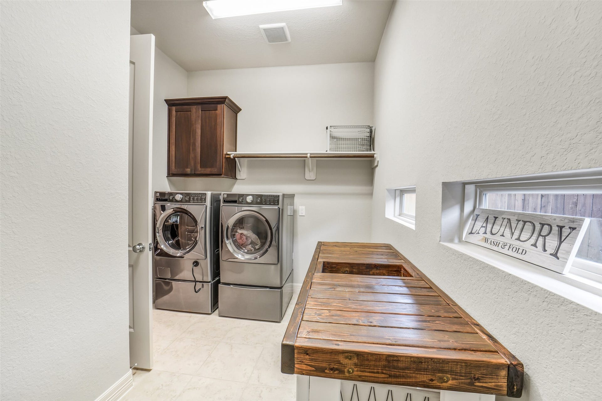 2721 Saddlehorn Trail, Katy, TX 77494 Oversized laundry room with built-in cabinetry, hanging rack with shelf, and plenty of space for a folding counter and another refrigerator or deep freeze.