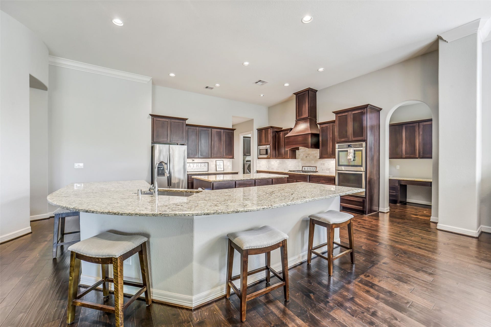 2721 Saddlehorn Trail, Katy, TX 77494 Designed for entertaining, this stunning kitchen showcases a massive granite island, extensive cabinetry, stainless steel appliances, and an open floor plan overlooking the living and dining areas.